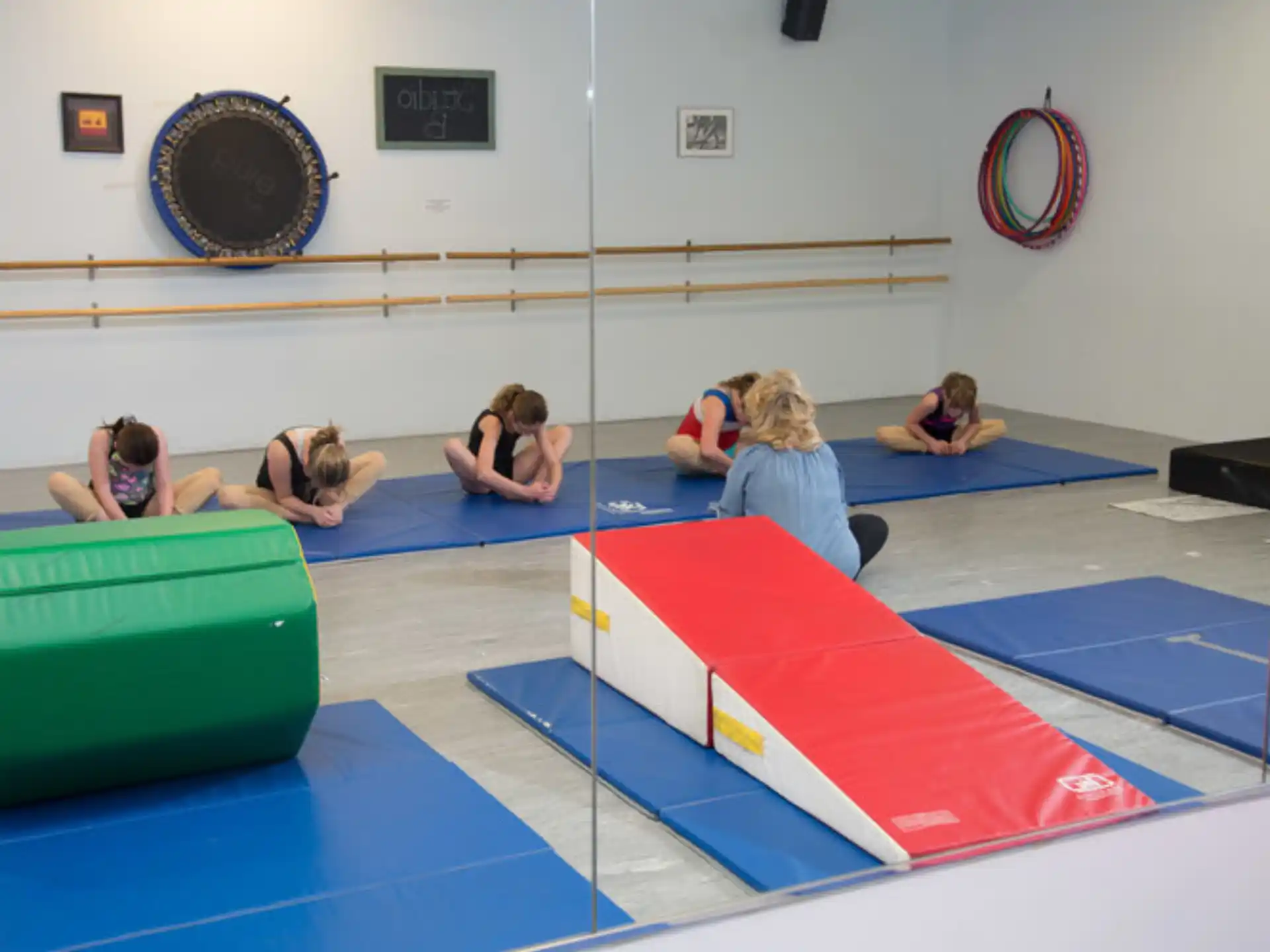 a group of people sitting on a mat in a room with a blue and white floor