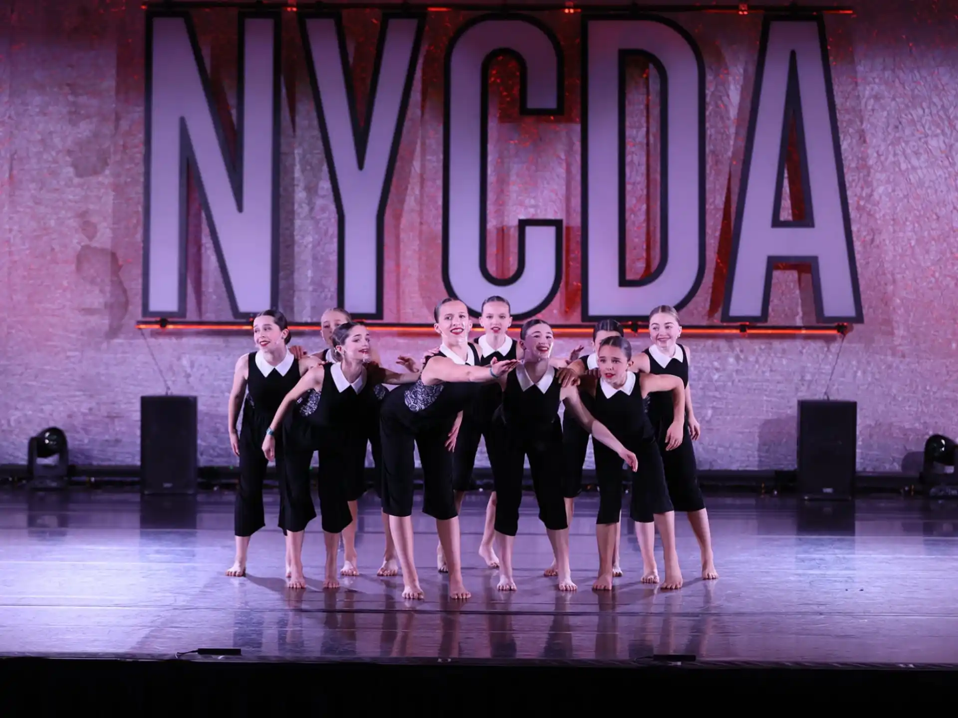 a group of women in black and white dresses on a stage
