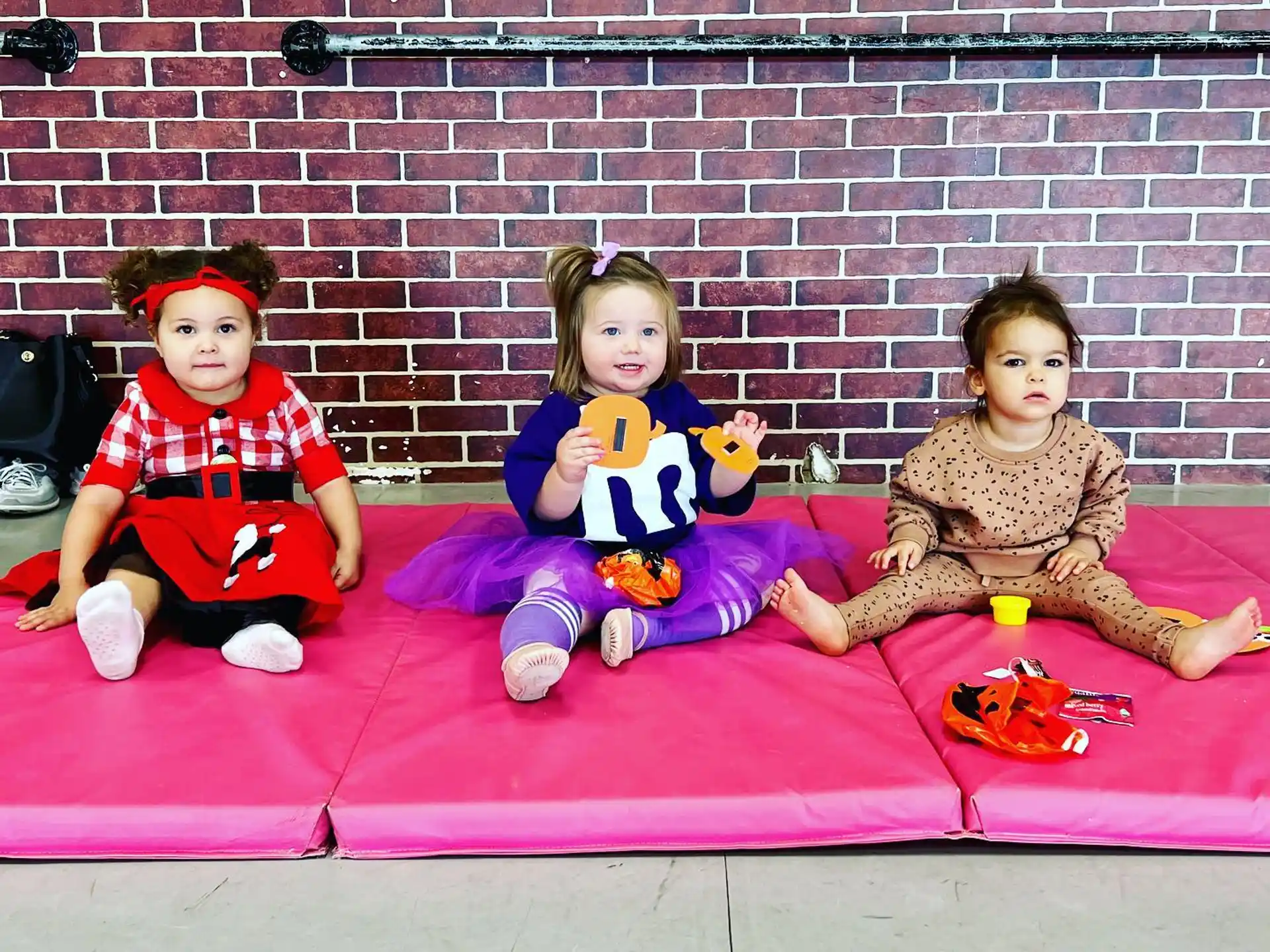 a group of children sitting on a red blanket