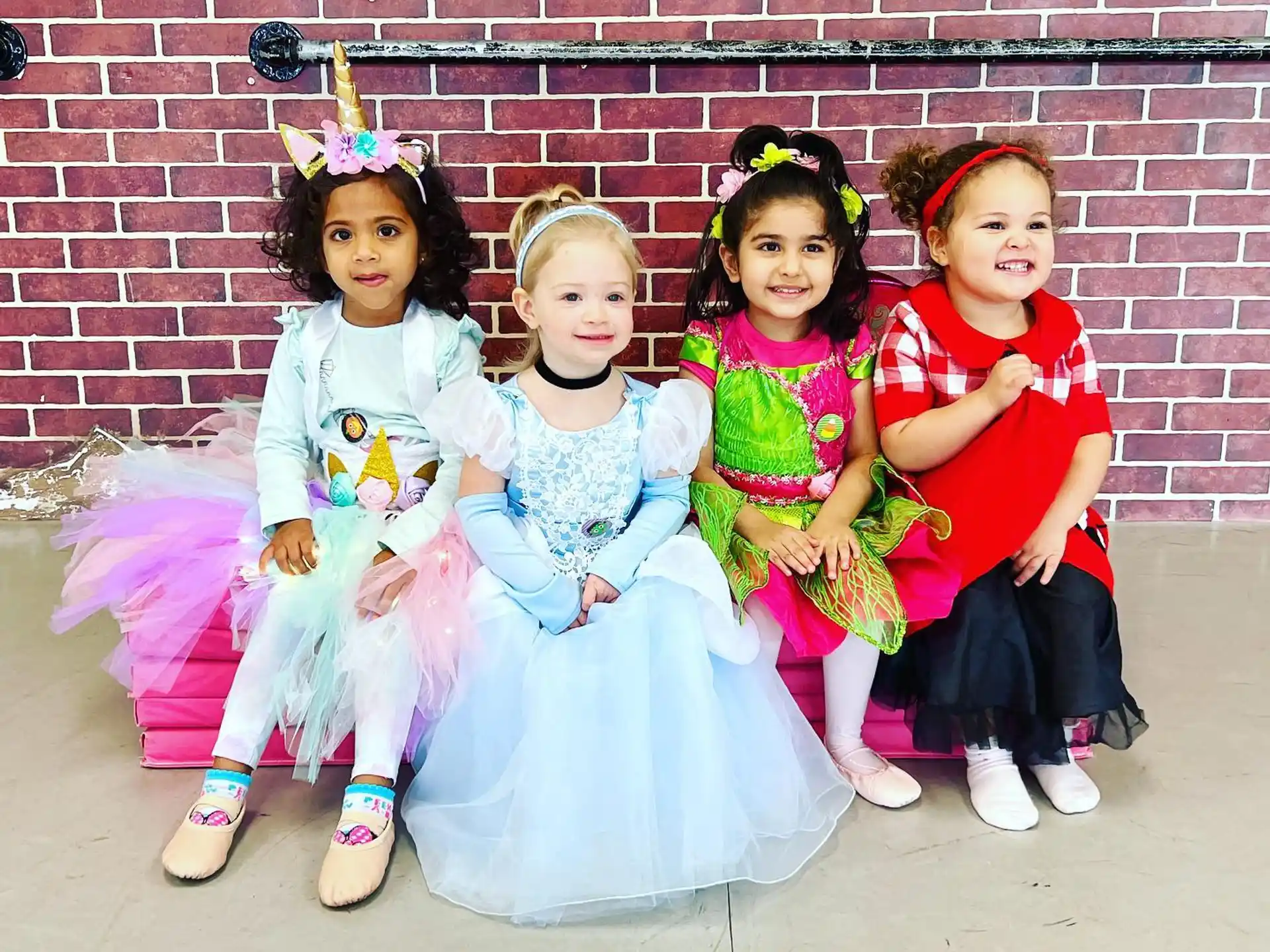 a group of girls in dresses and dresses sitting on a bench