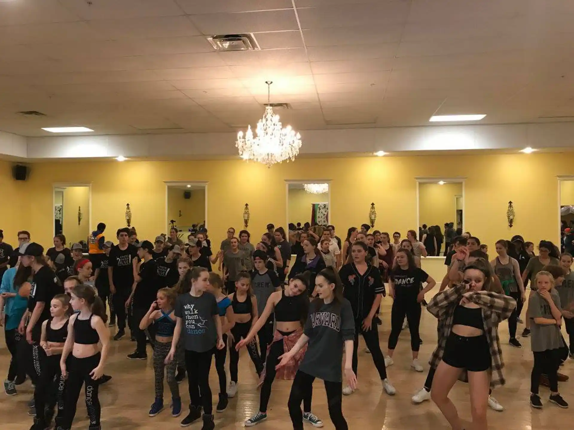 a group of people dancing in a room with a chandelier