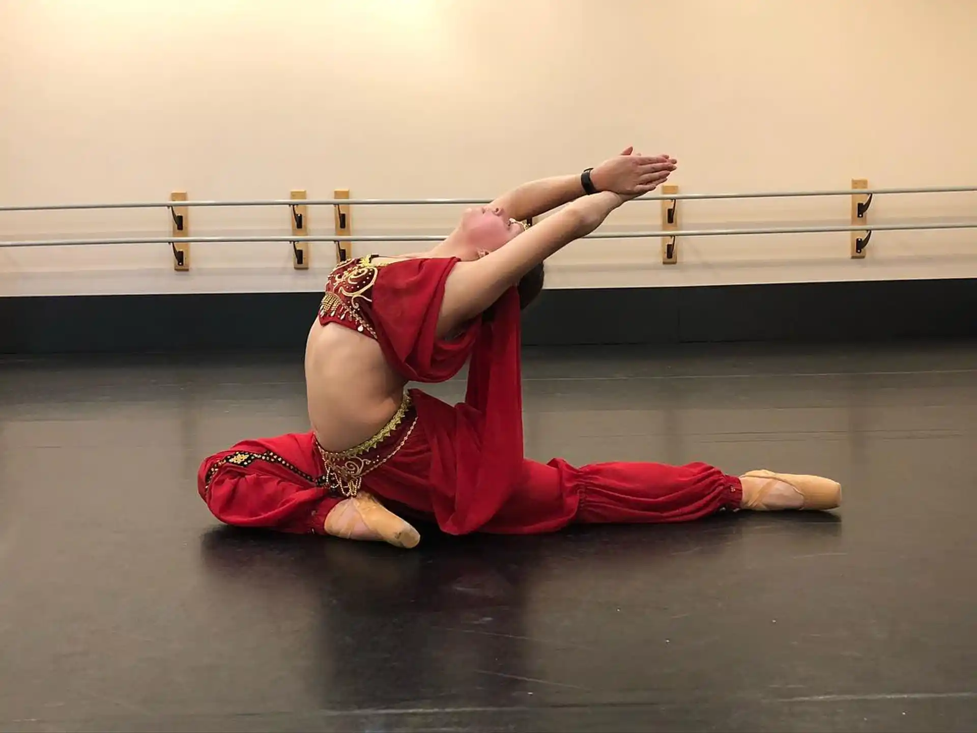 a person in a red dress doing a handstand on a wood floor