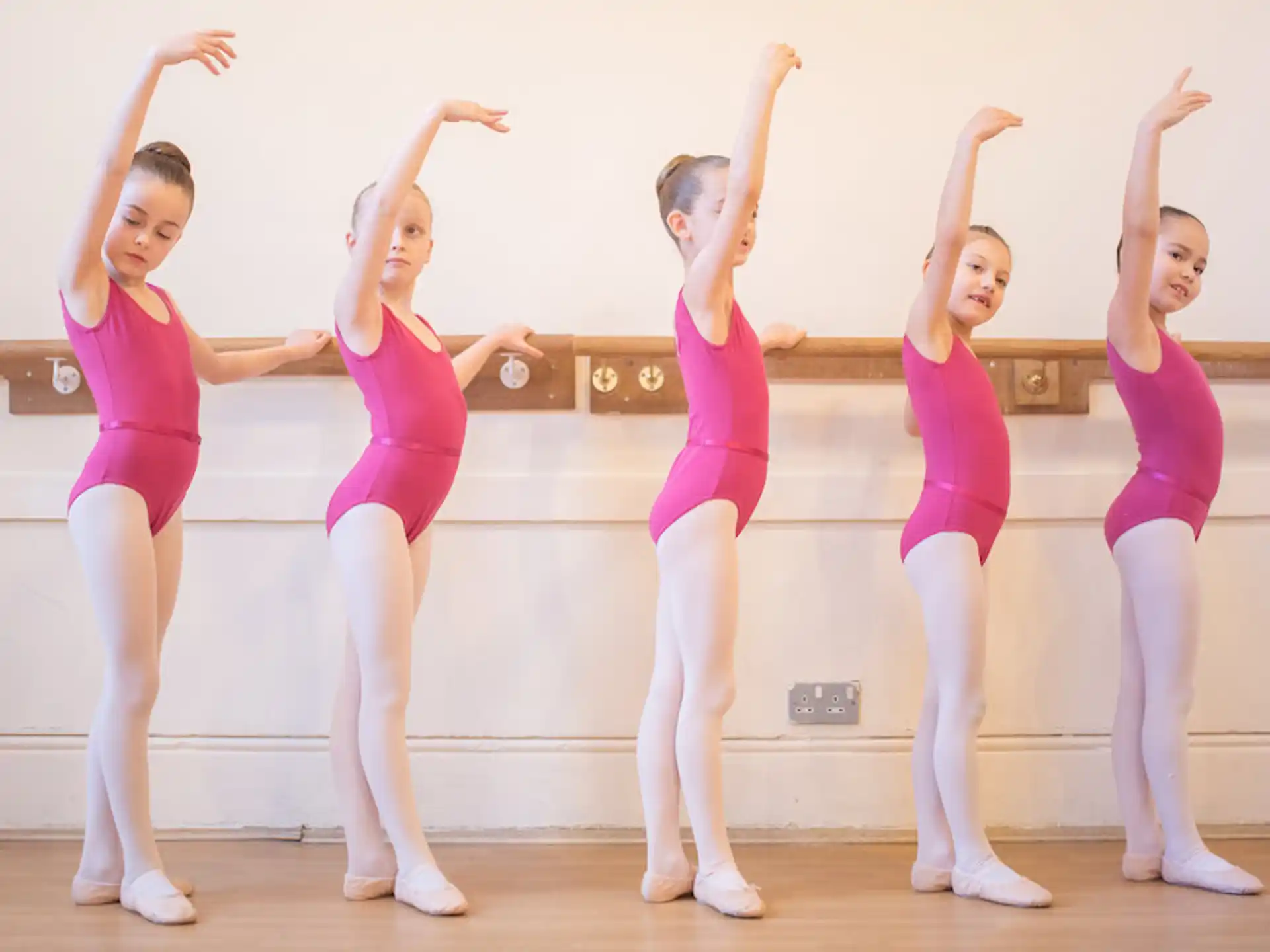 a group of girls in pink leotards posing for a photo