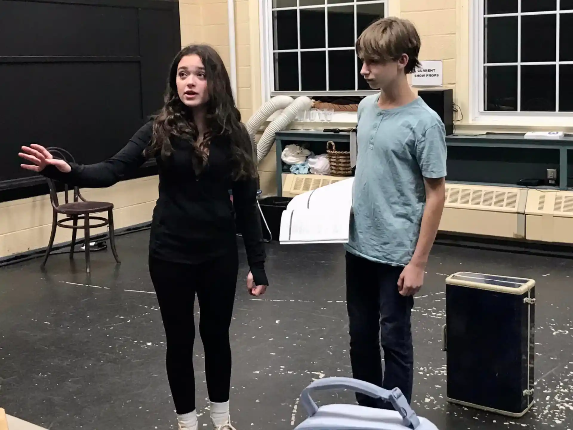 a person and a boy standing in a room with boxes and a window