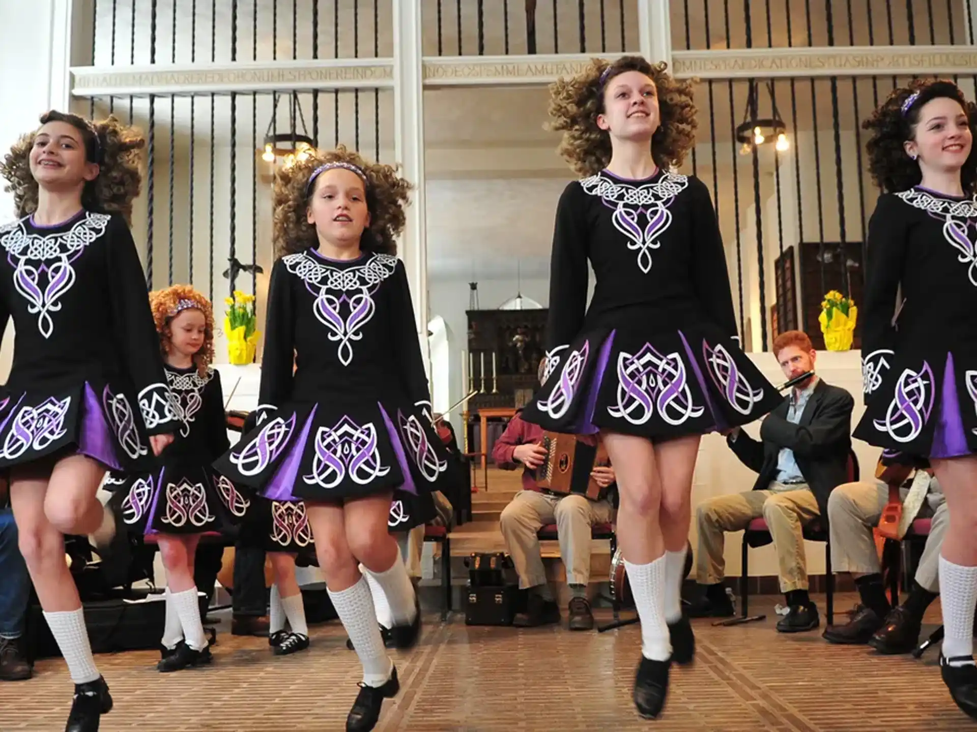 a group of women in black and purple dresses on a stage