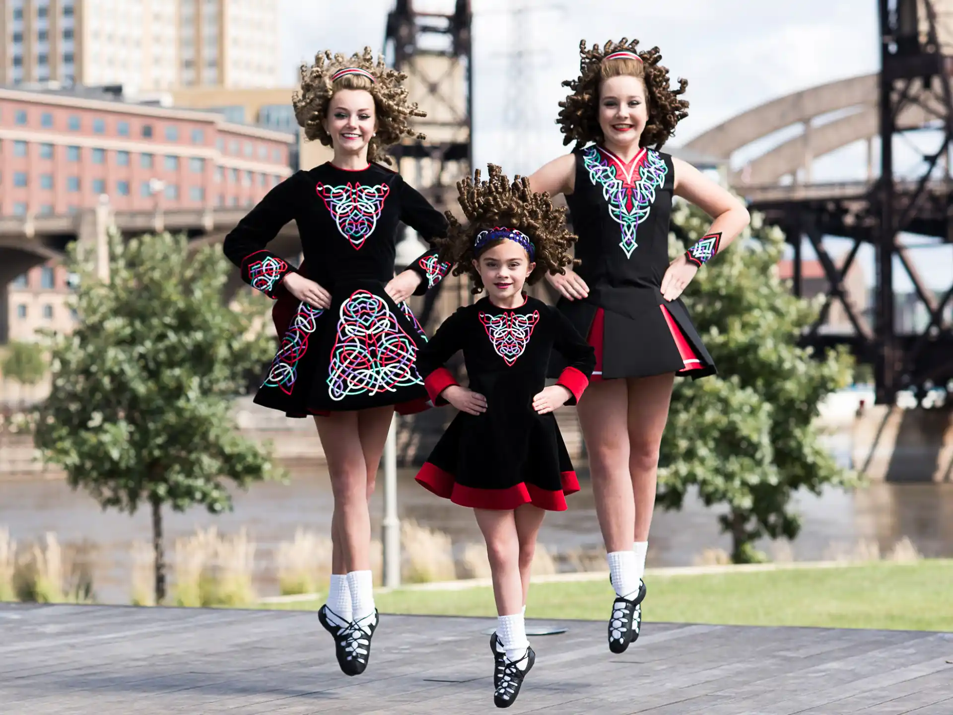 a group of women in black and red dresses running on a street