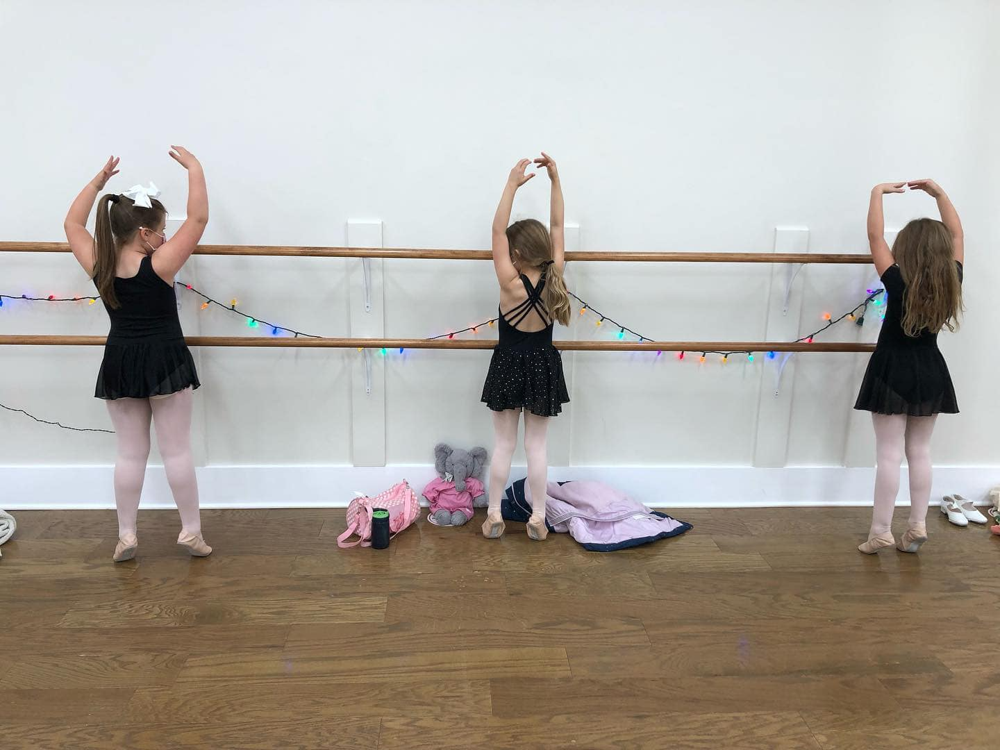 a group of girls in black dresses holding onto a rope