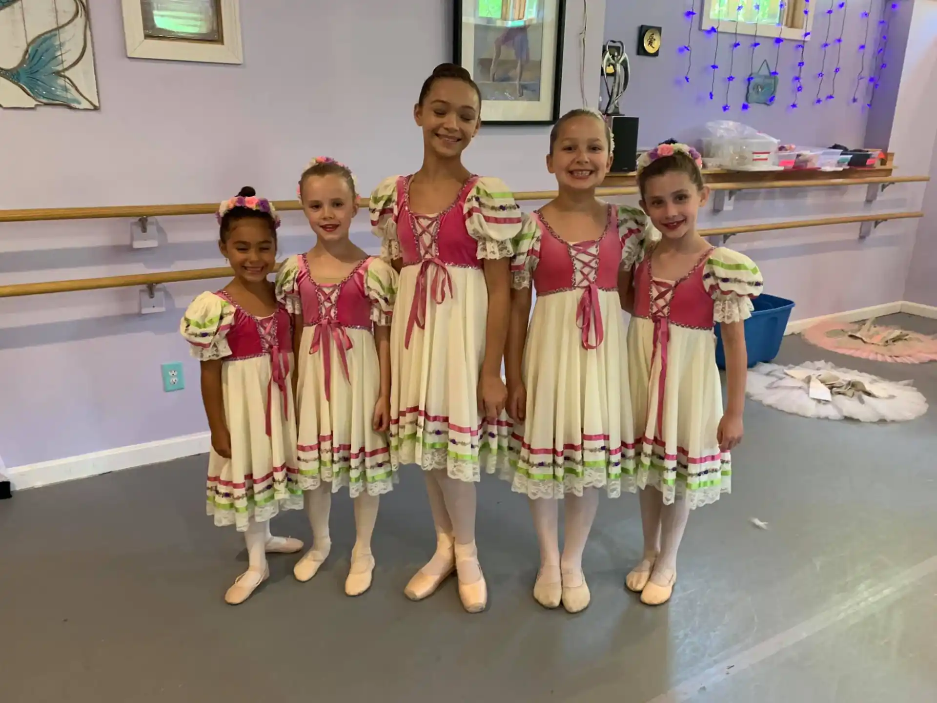 a group of girls in dresses and dresses standing in front of a wall