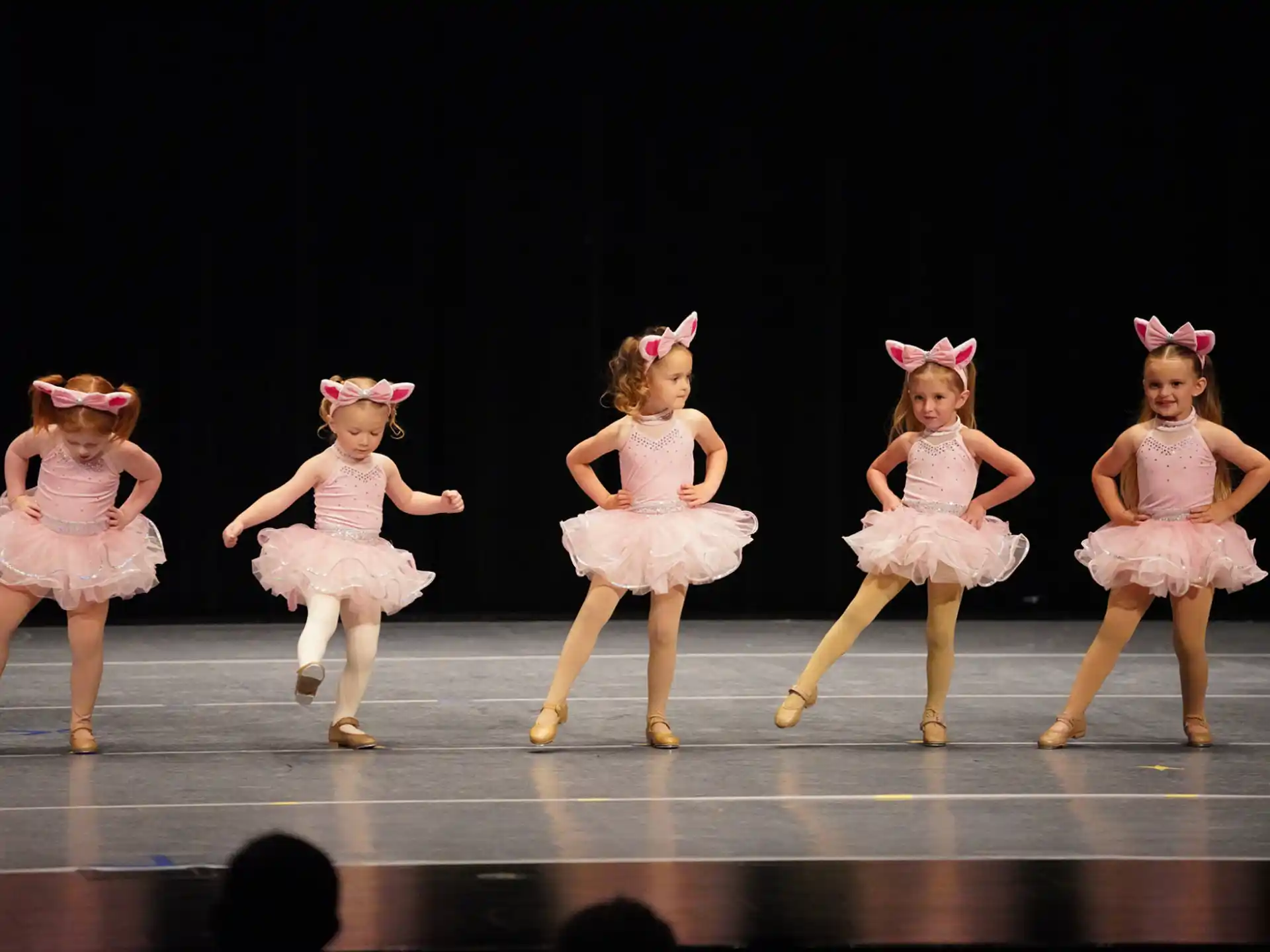 a group of girls wearing dresses and dancing on a stage