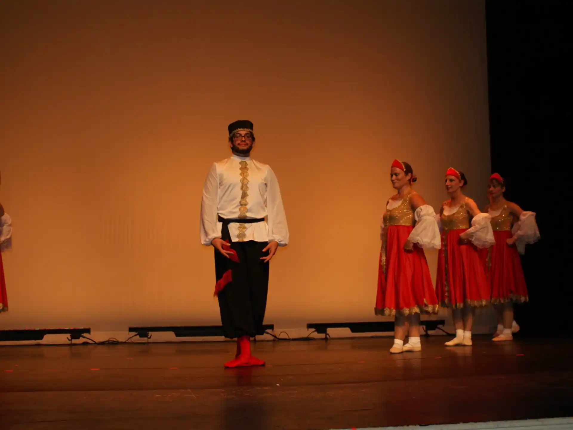 a person standing on a stage with a group of women in red dresses