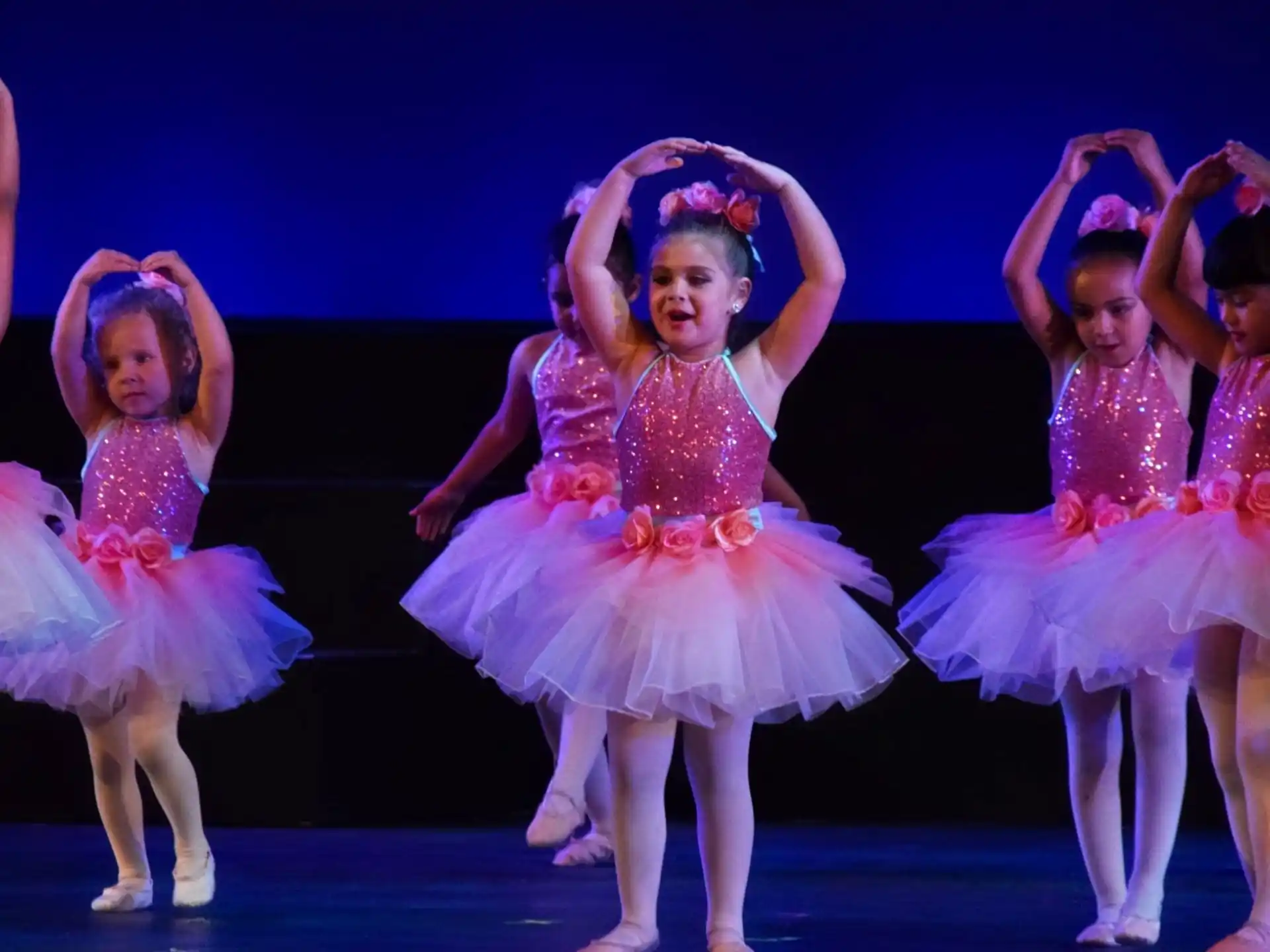 a group of girls wearing dresses and dancing on a stage