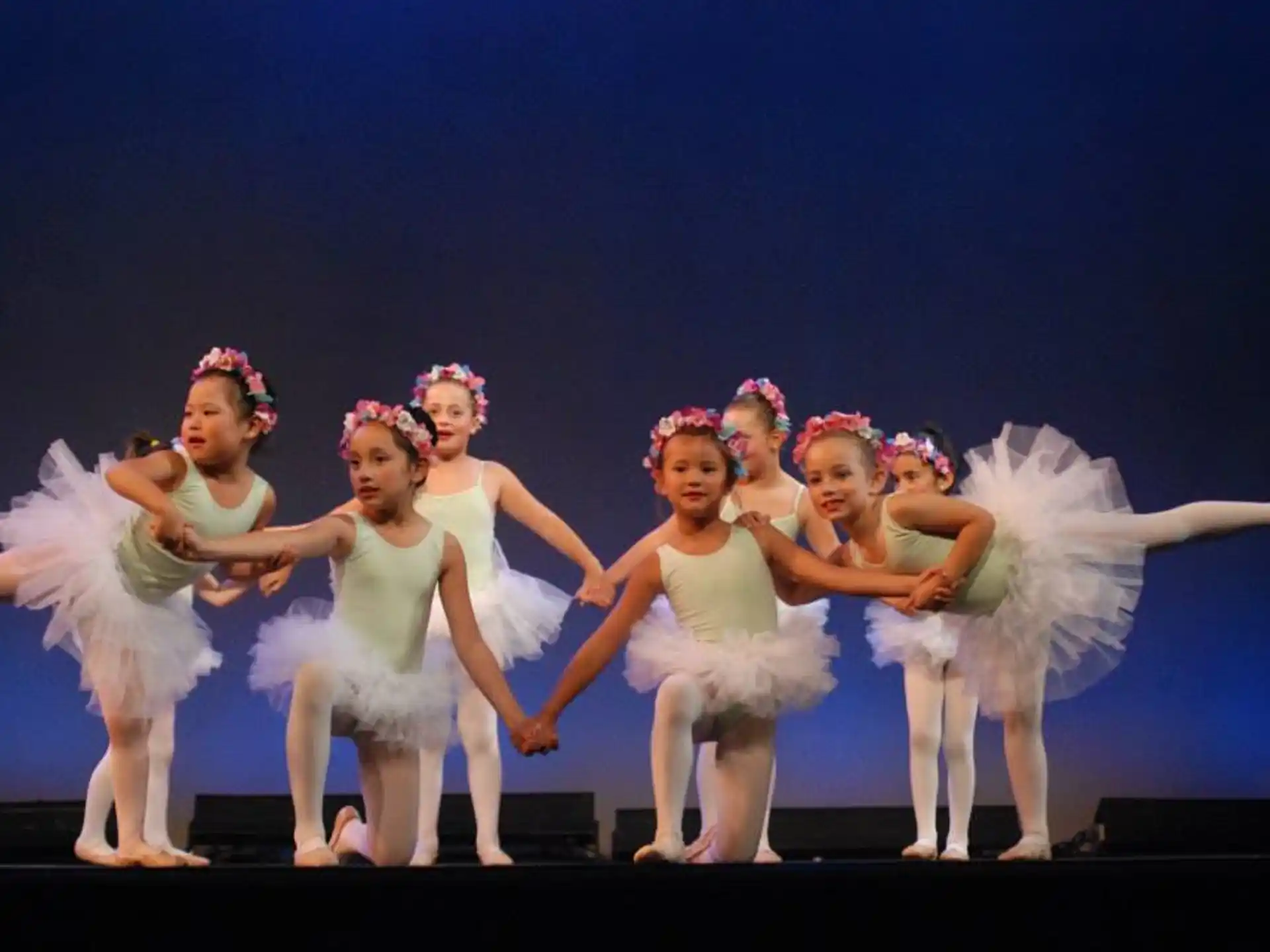 a group of girls in white dresses dancing on a stage