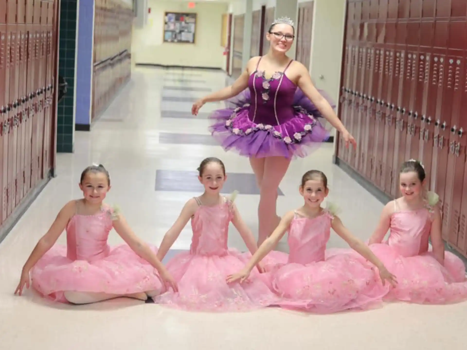 a person and several girls in pink dresses in a pool