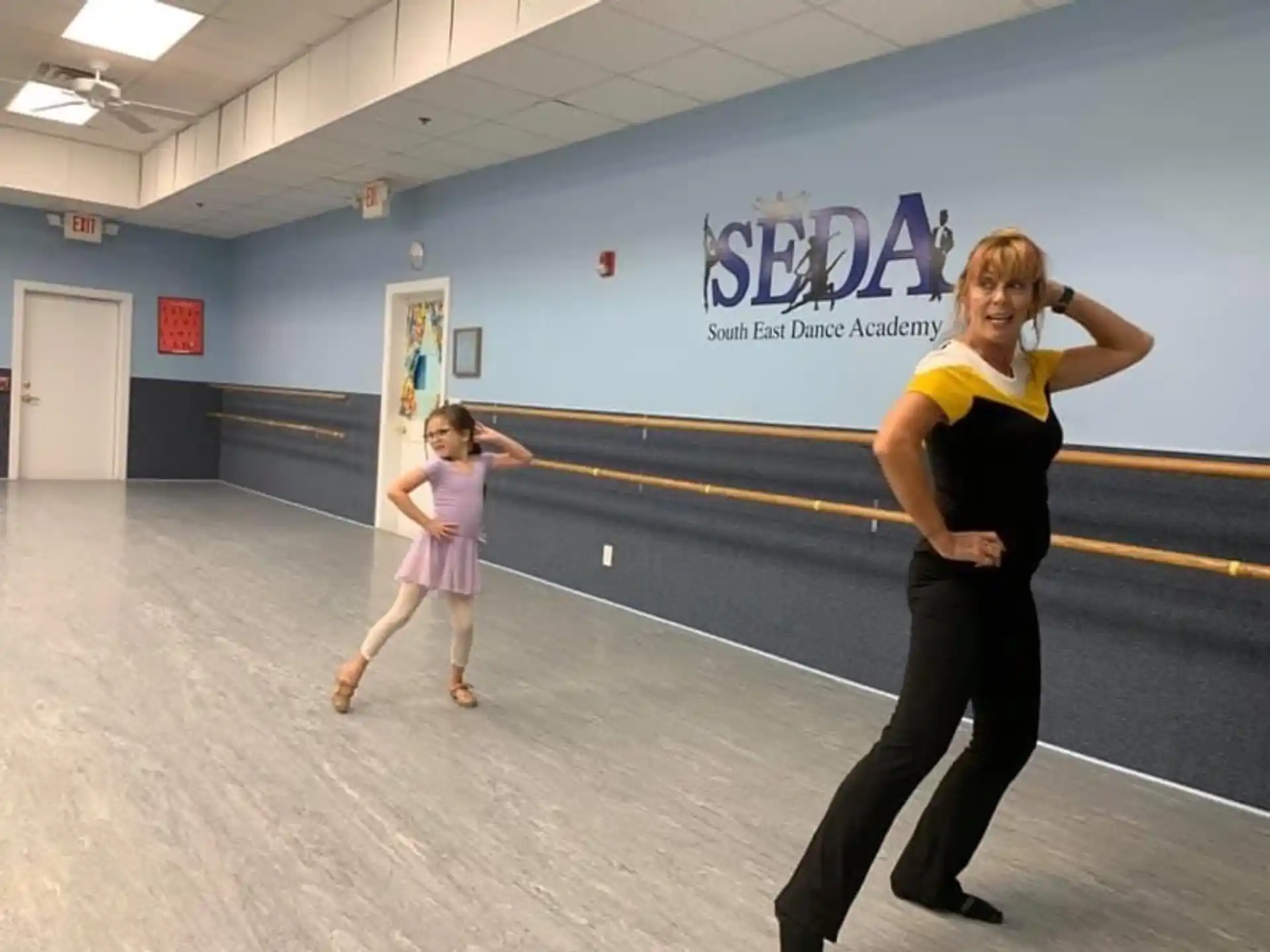 a woman and a girl dancing in a gymnasium