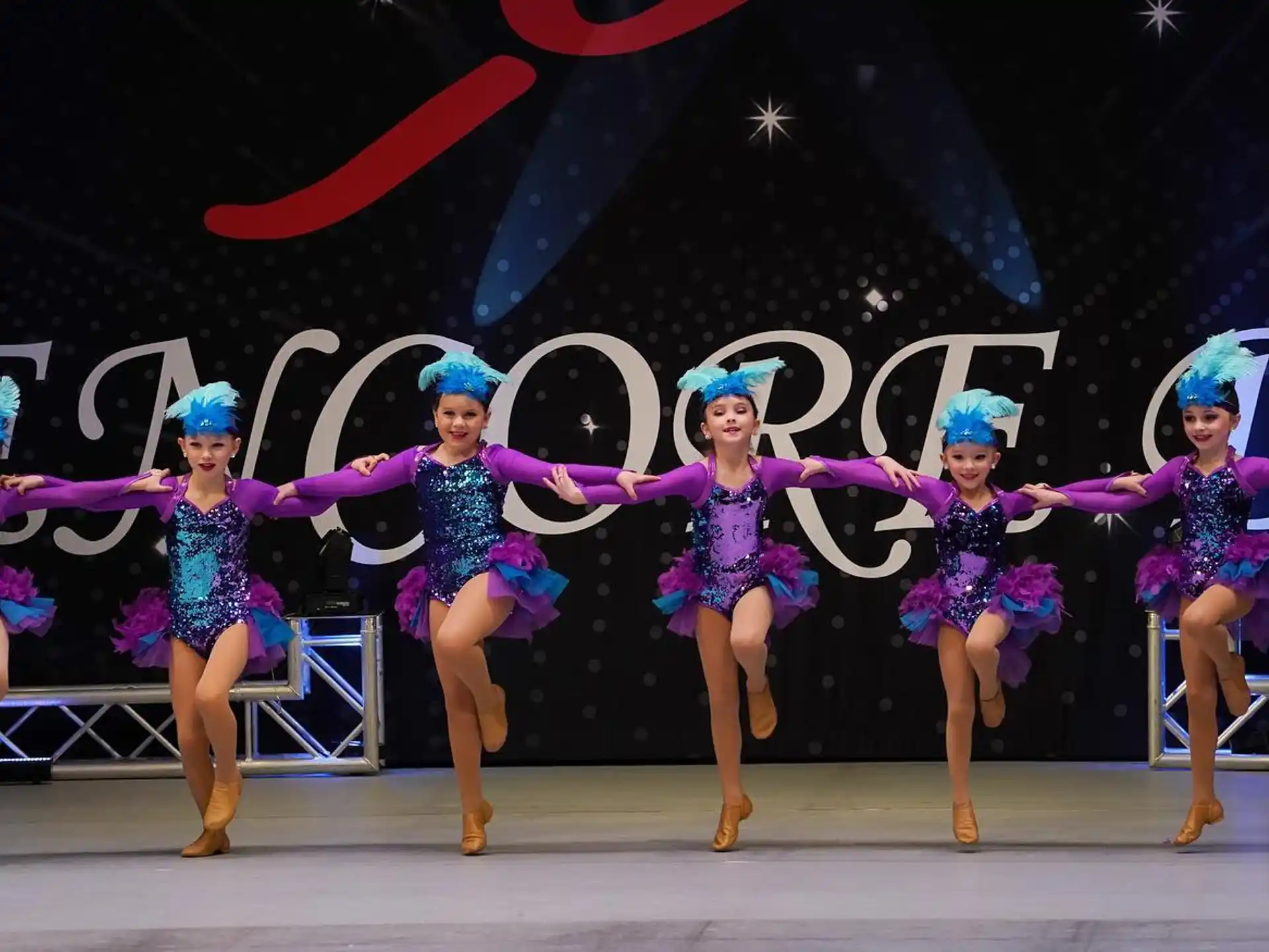 a group of women in blue and white dresses dancing on a stage