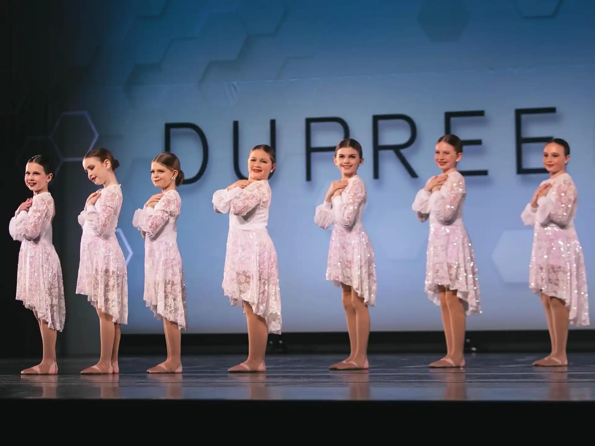 a group of girls in dresses on a stage