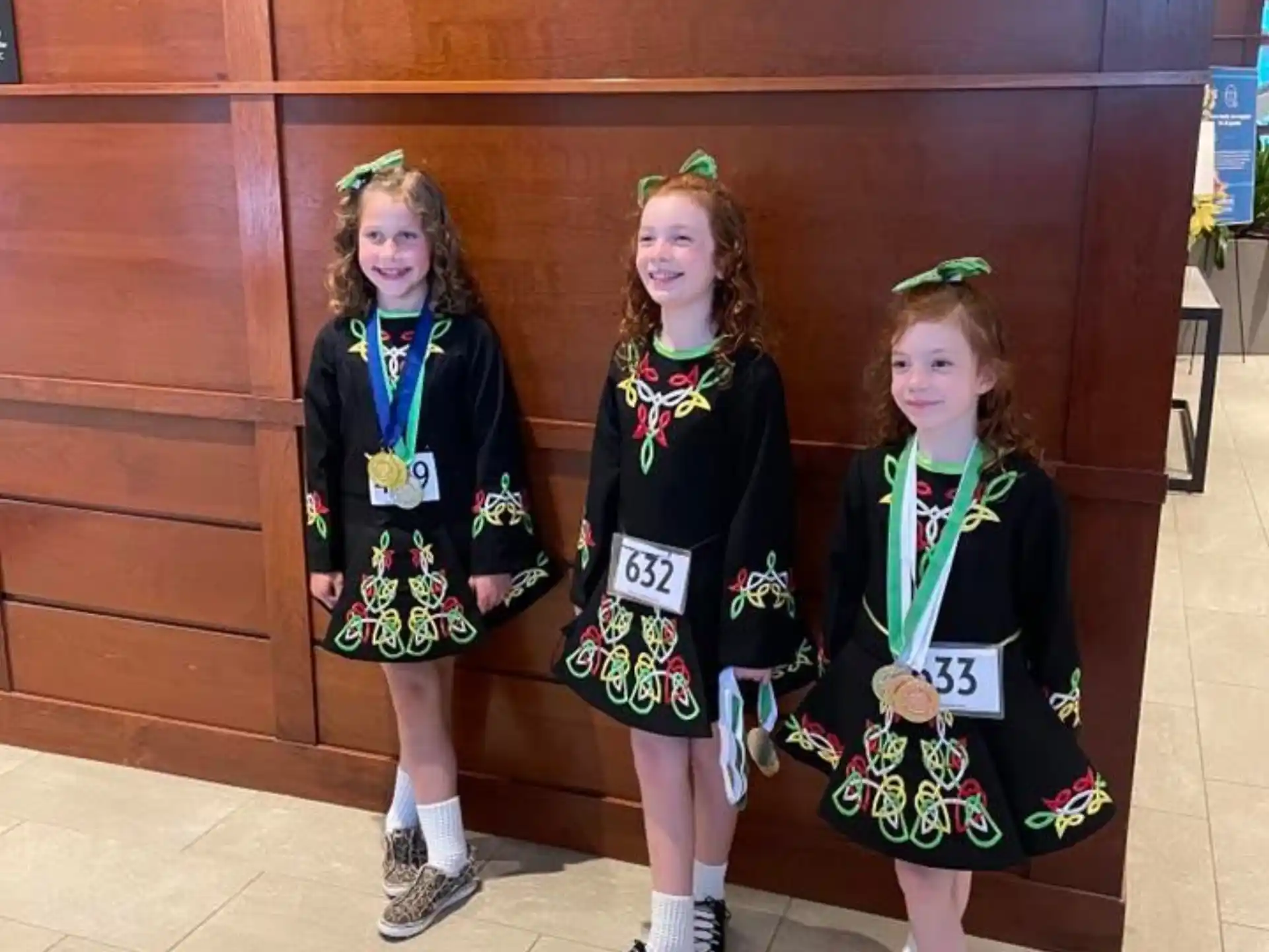 a group of girls wearing medals and standing in front of a wooden cabinet