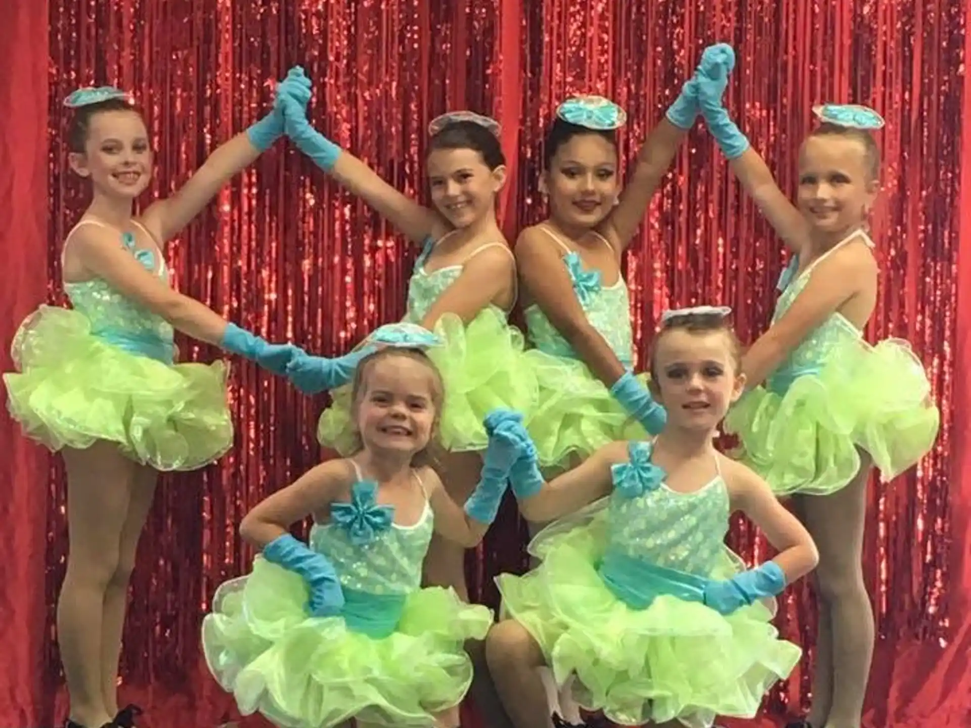 a group of girls in dresses and blue gloves posing for a photo
