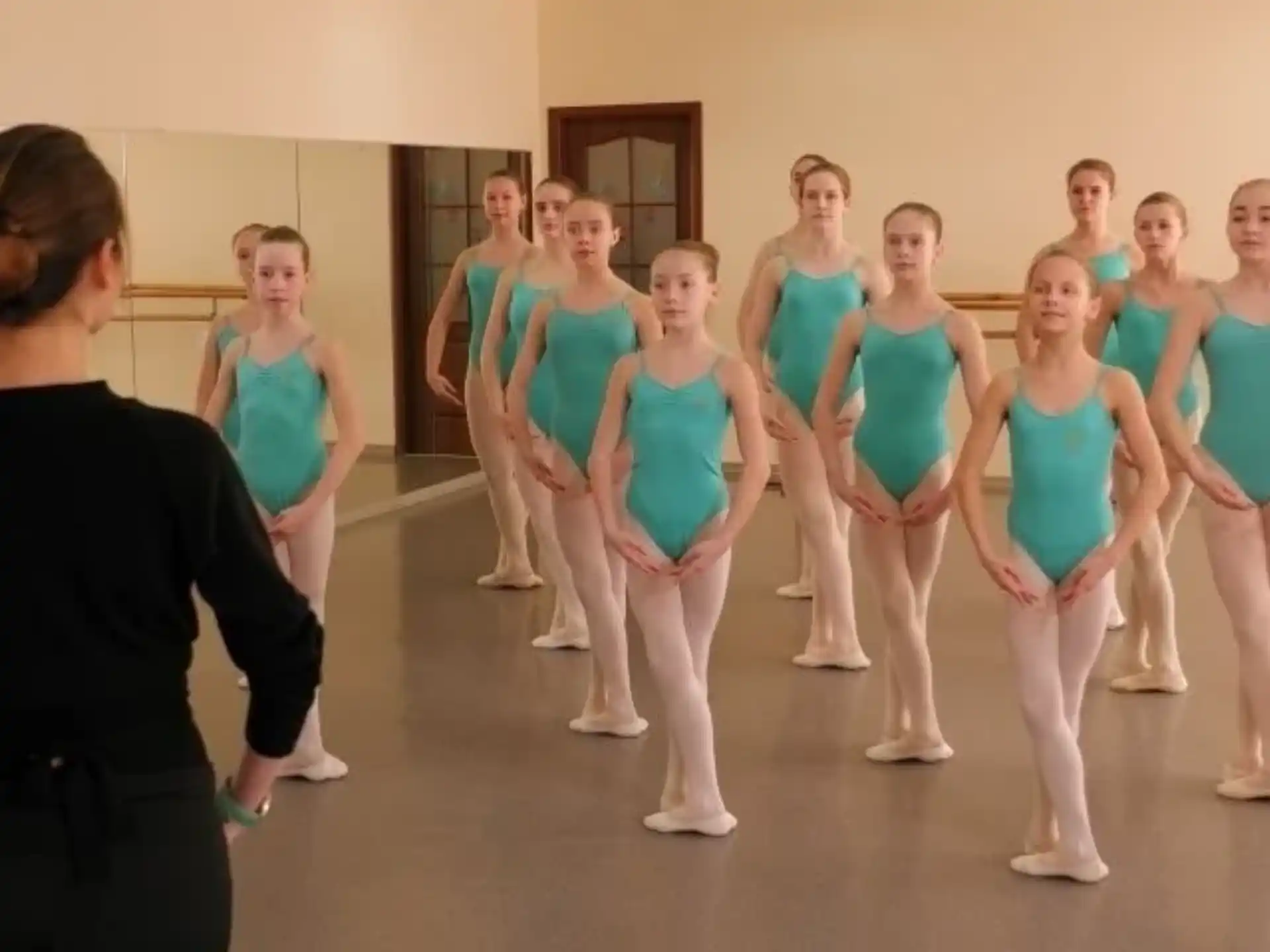 a person standing in front of a group of girls in a room