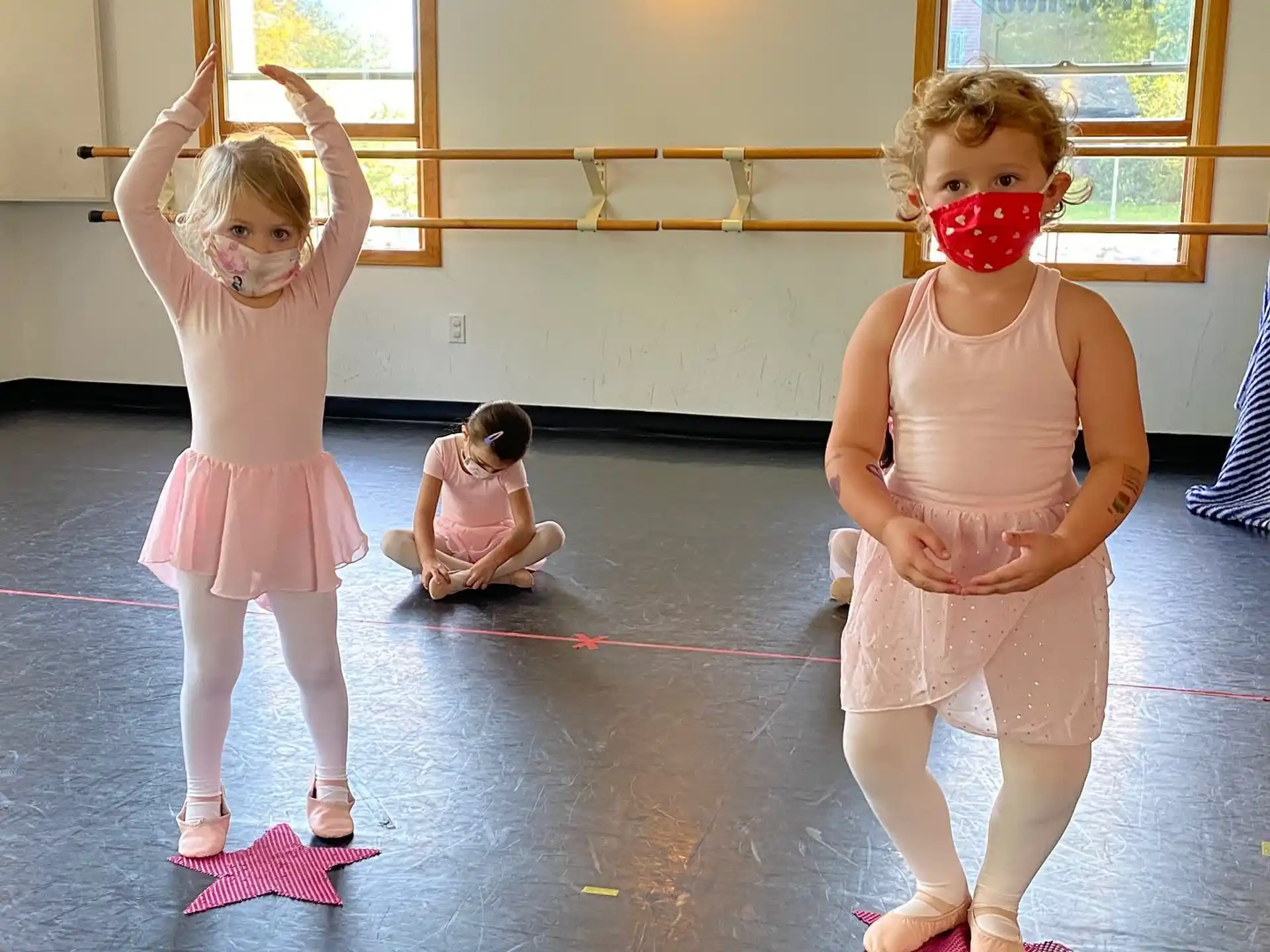 a group of girls wearing pink and white dresses and standing on a mat