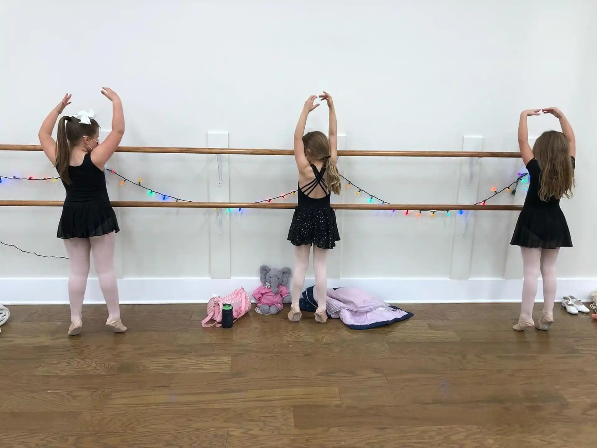 a group of girls in black dresses holding onto a rope