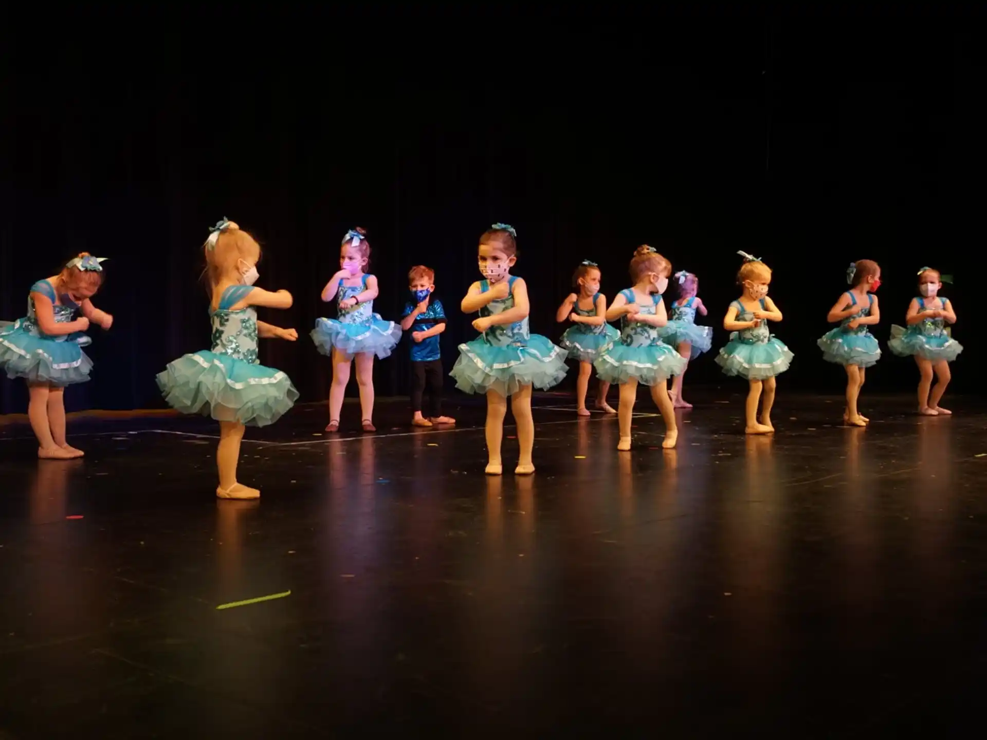 a group of girls in blue dresses on a stage