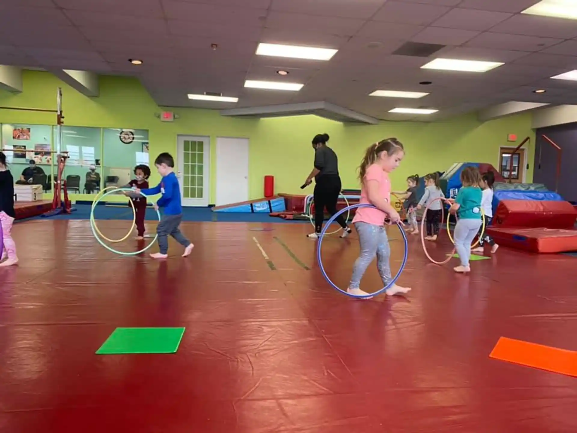 a group of children playing with hoops in a room with green walls