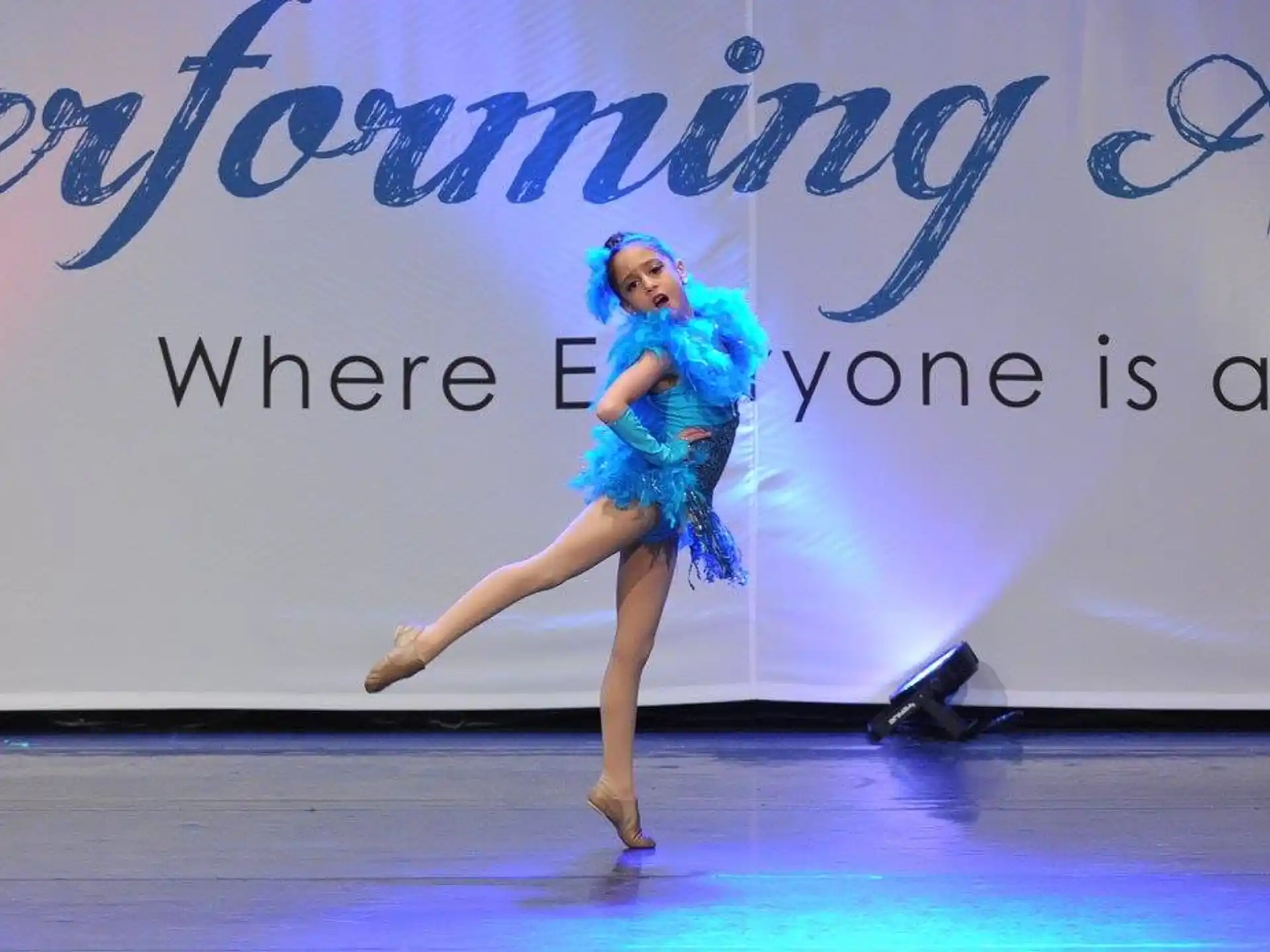 a person in a blue dress dancing on a stage
