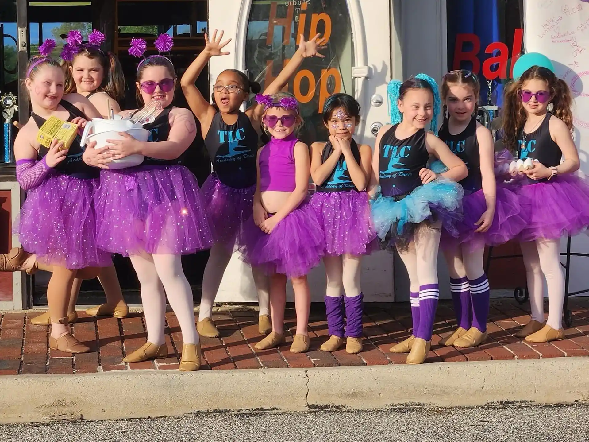 a group of girls in purple and black dresses posing for a photo