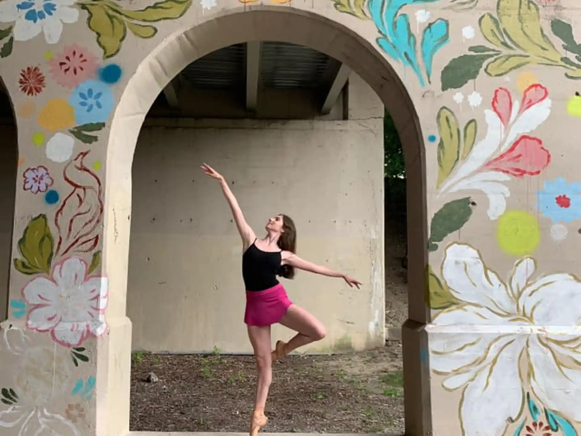 a woman posing in front of a wall with flowers