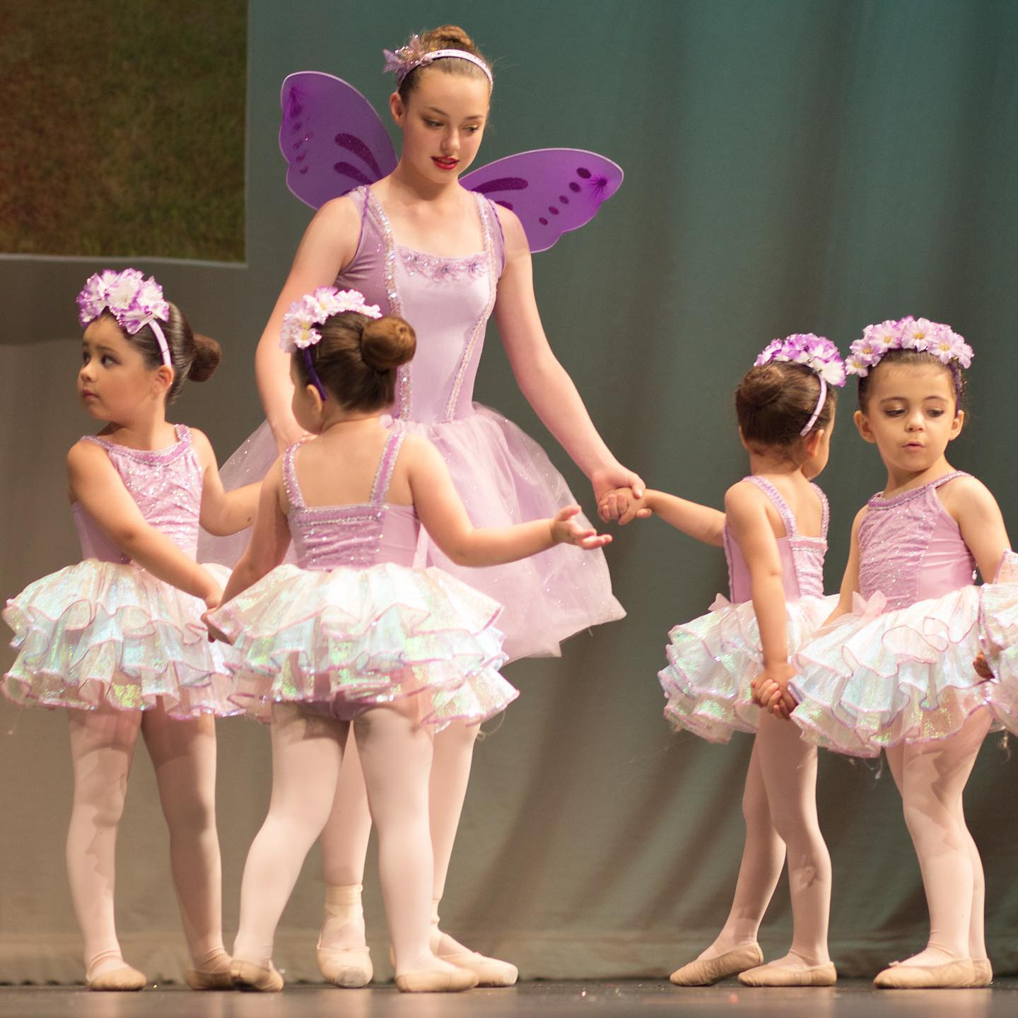 a group of girls wearing dresses and dancing