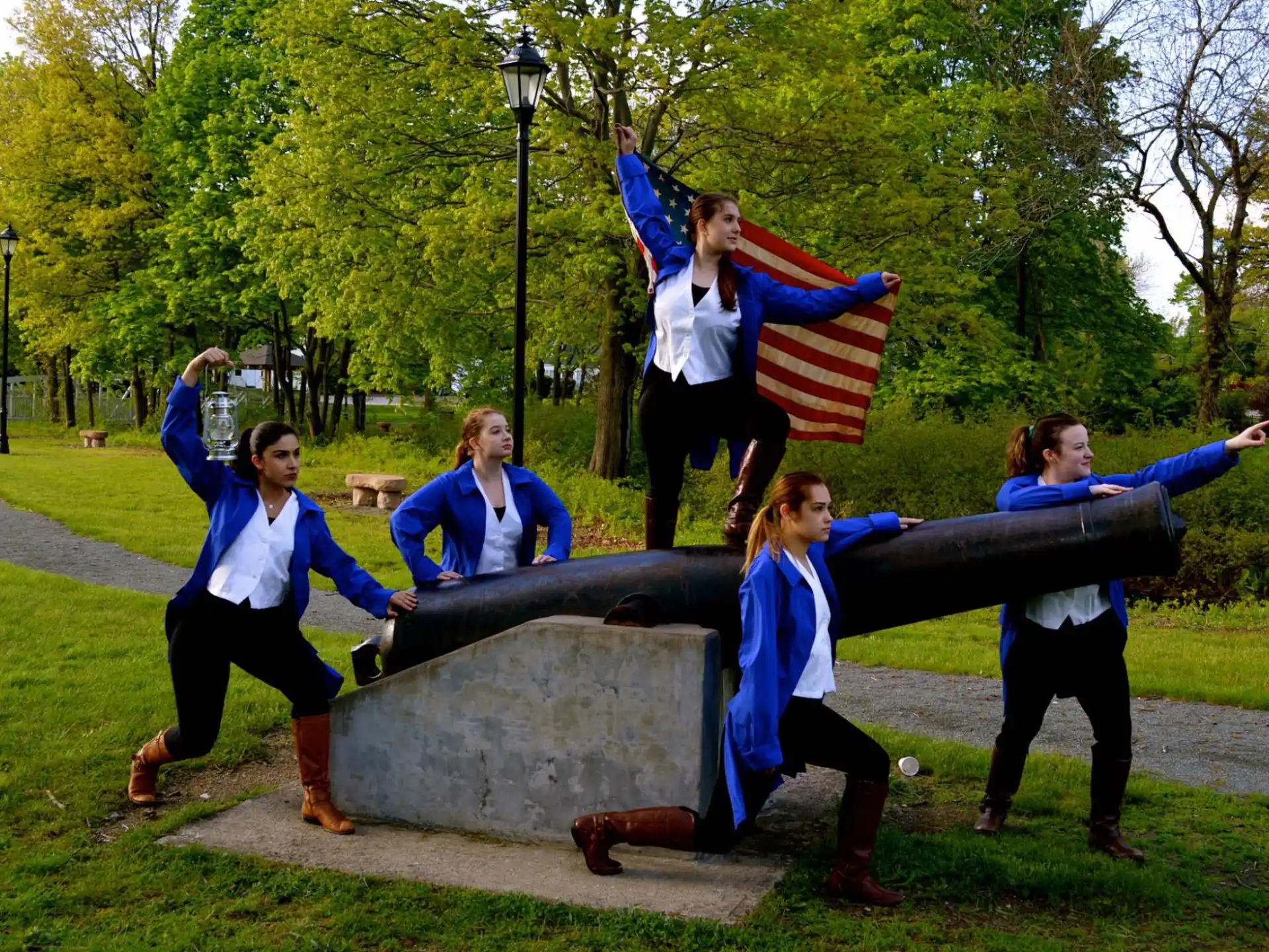 a group of women jumping on a statue in a park