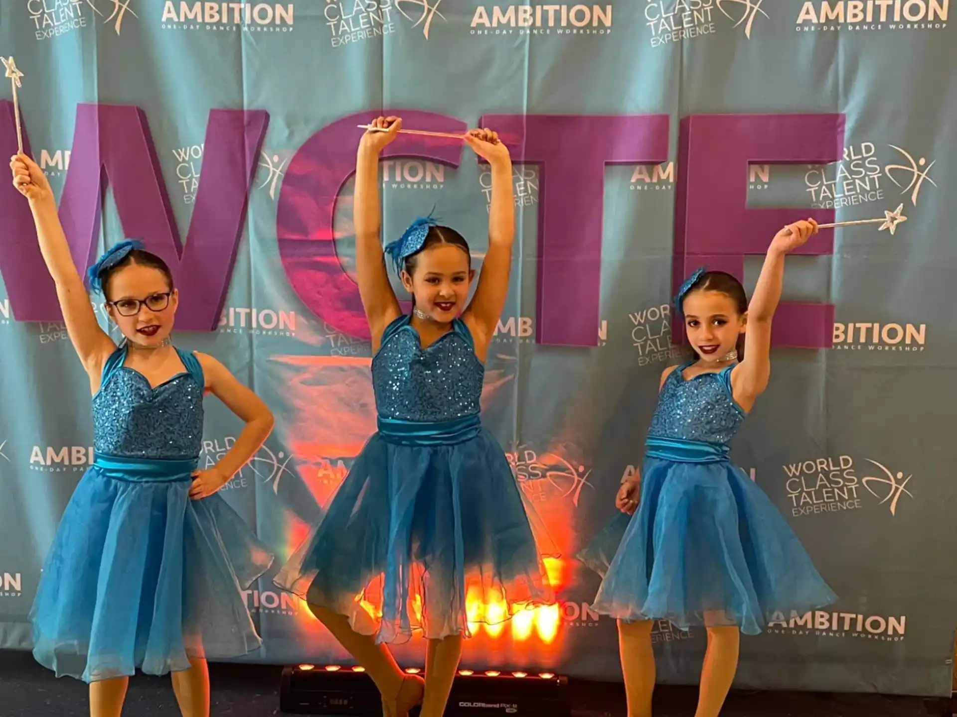 a group of girls in blue dresses dancing on a stage