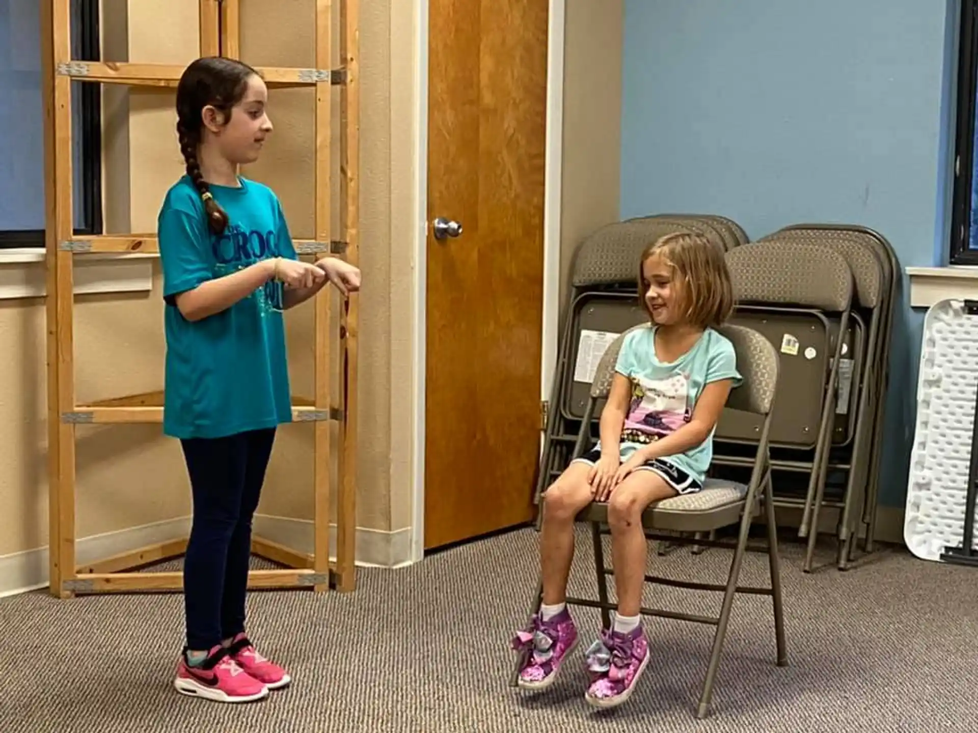 a girl sitting in a chair next to a girl in a chair