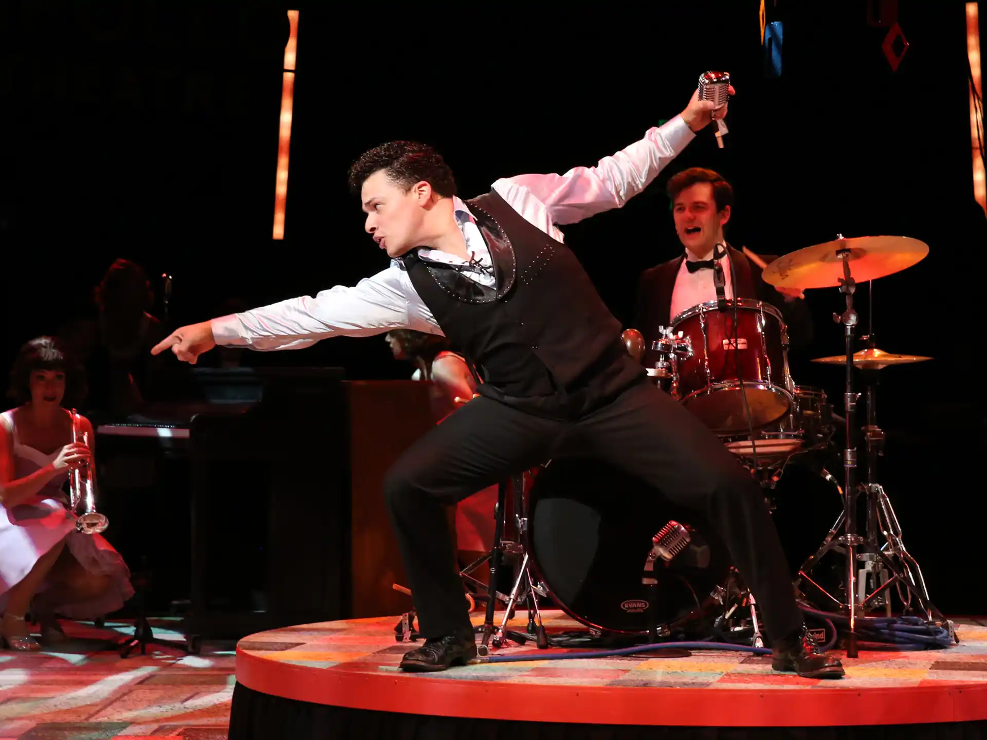 a person on a stage with a microphone and a drum set