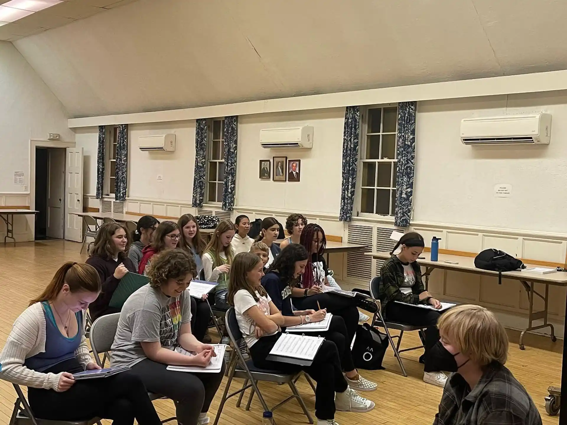 a group of people sitting in a room with laptops