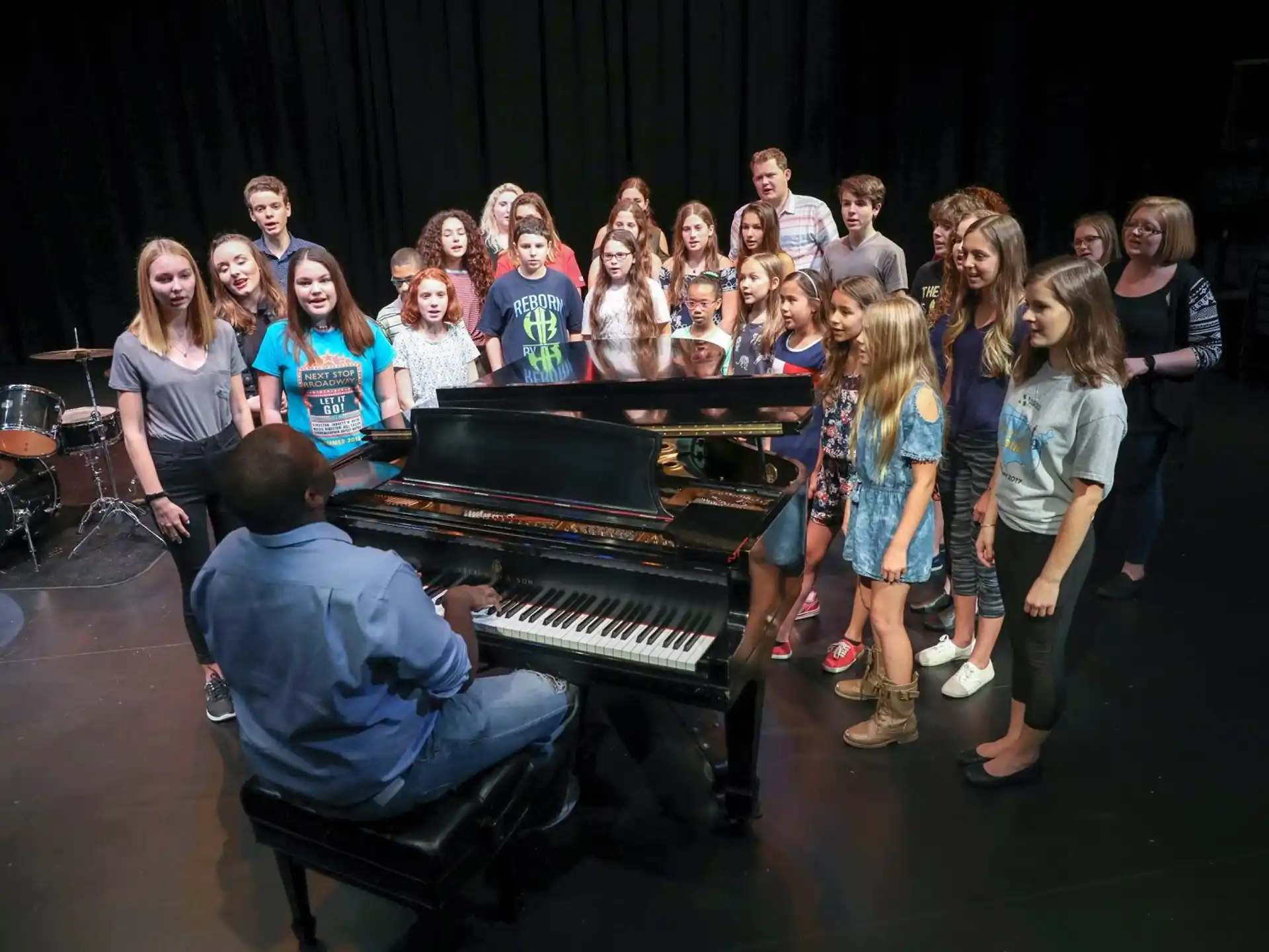 a group of people standing around a piano