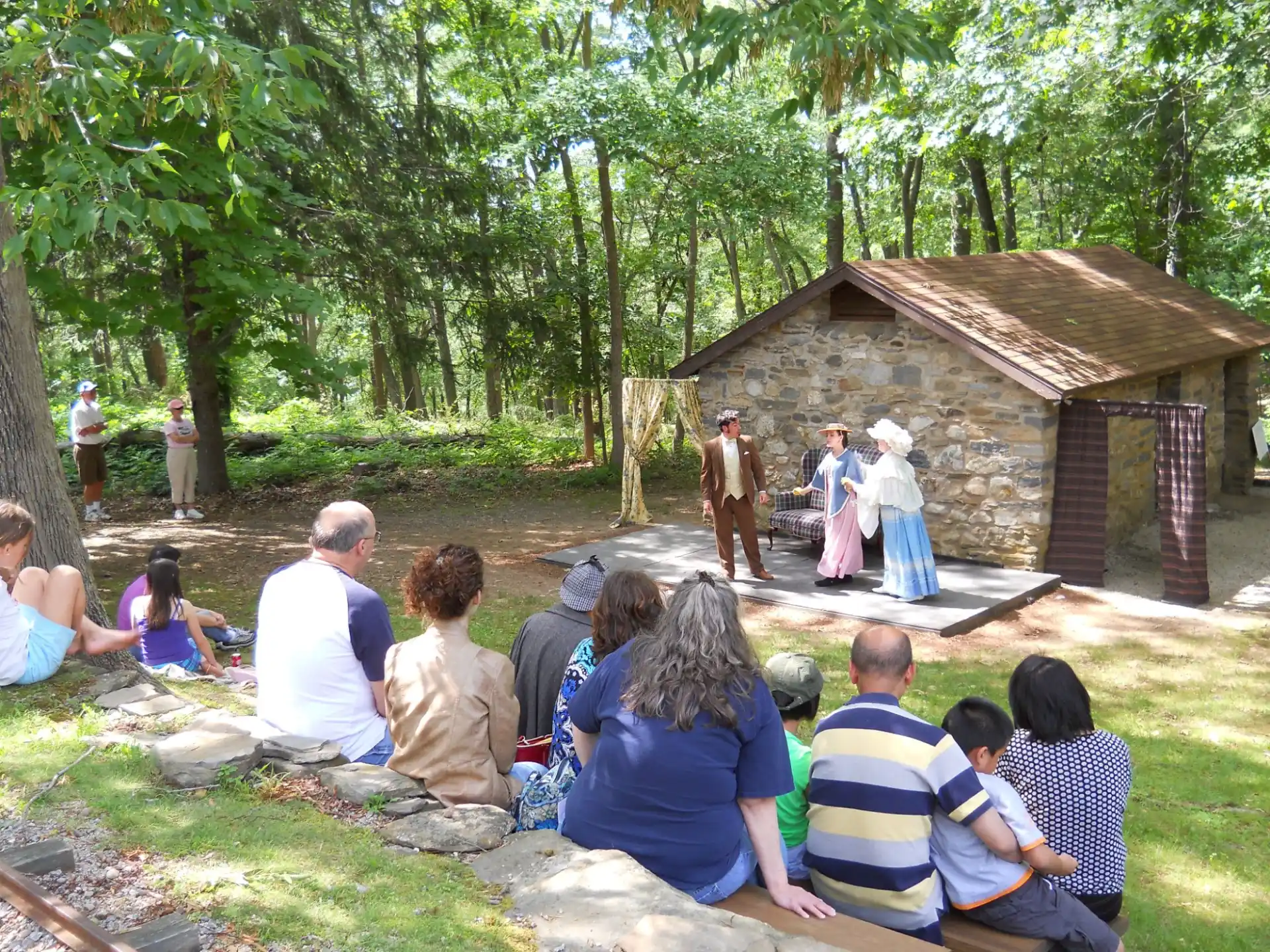a group of people sitting on the ground watching a person play a musical instrument