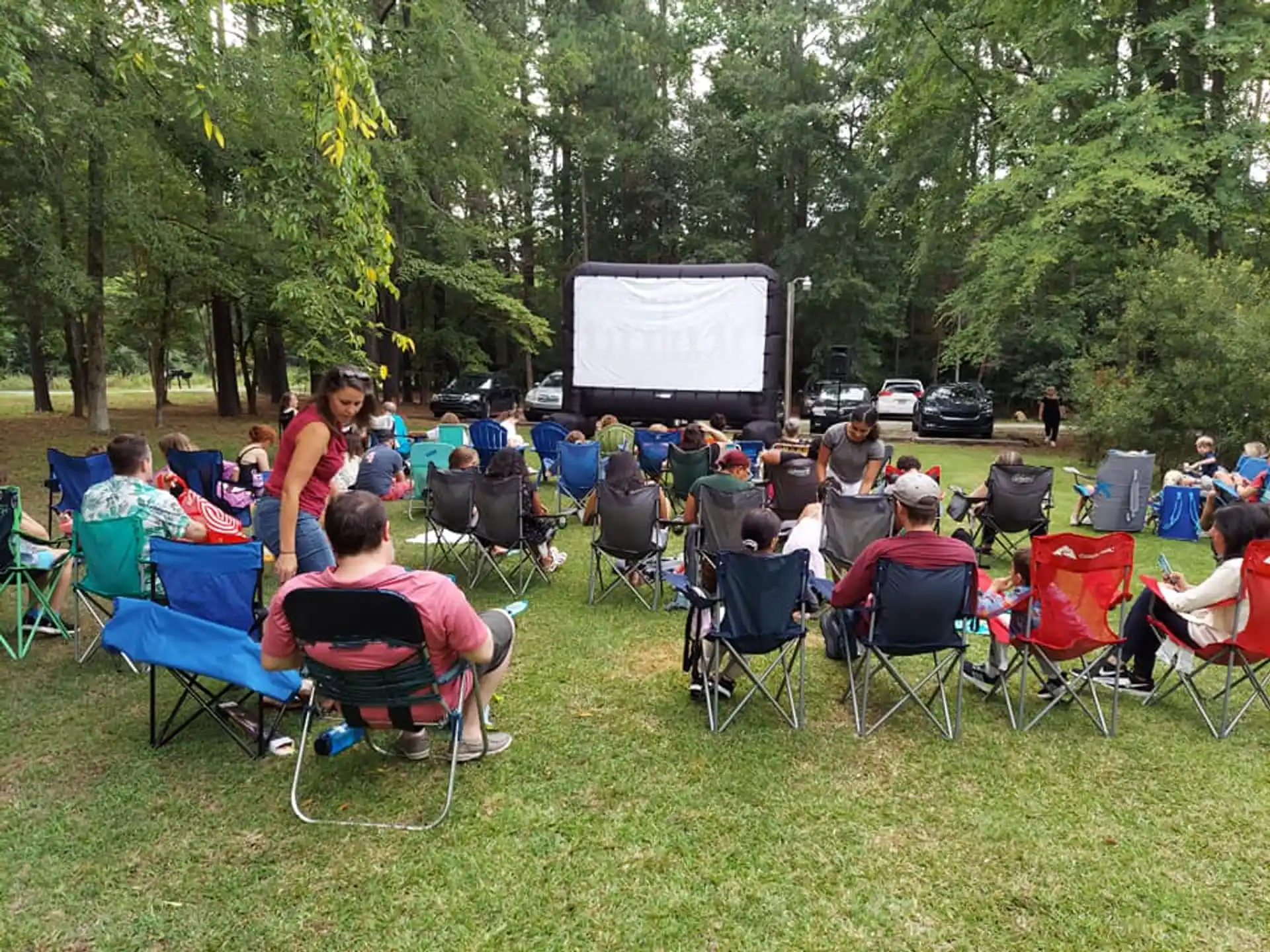 a group of people sitting in chairs in a circle in front of a screen