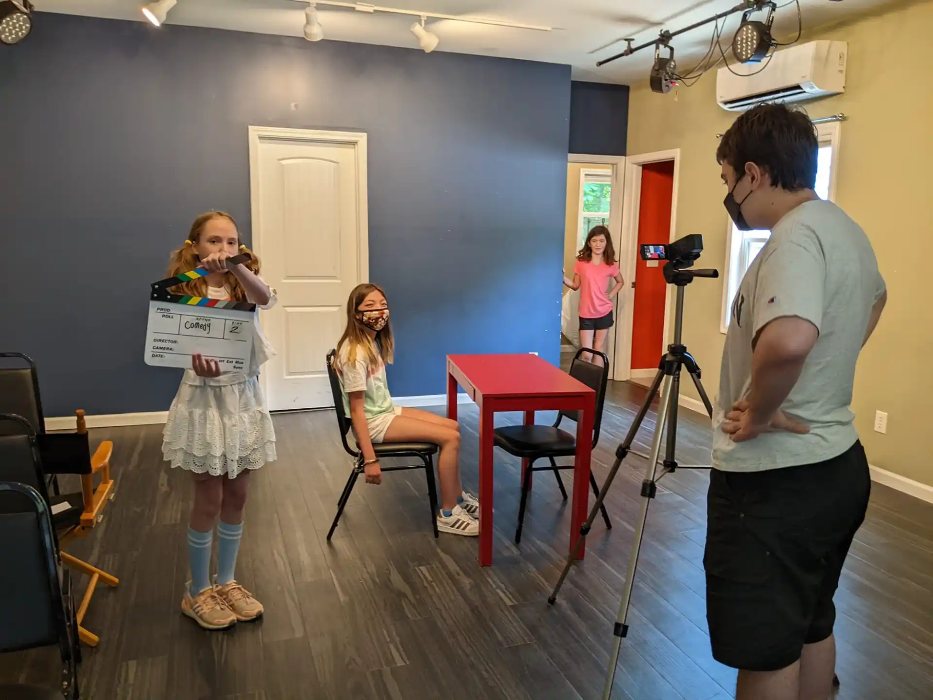 a man and a woman in a room with a camera and a woman holding a sign