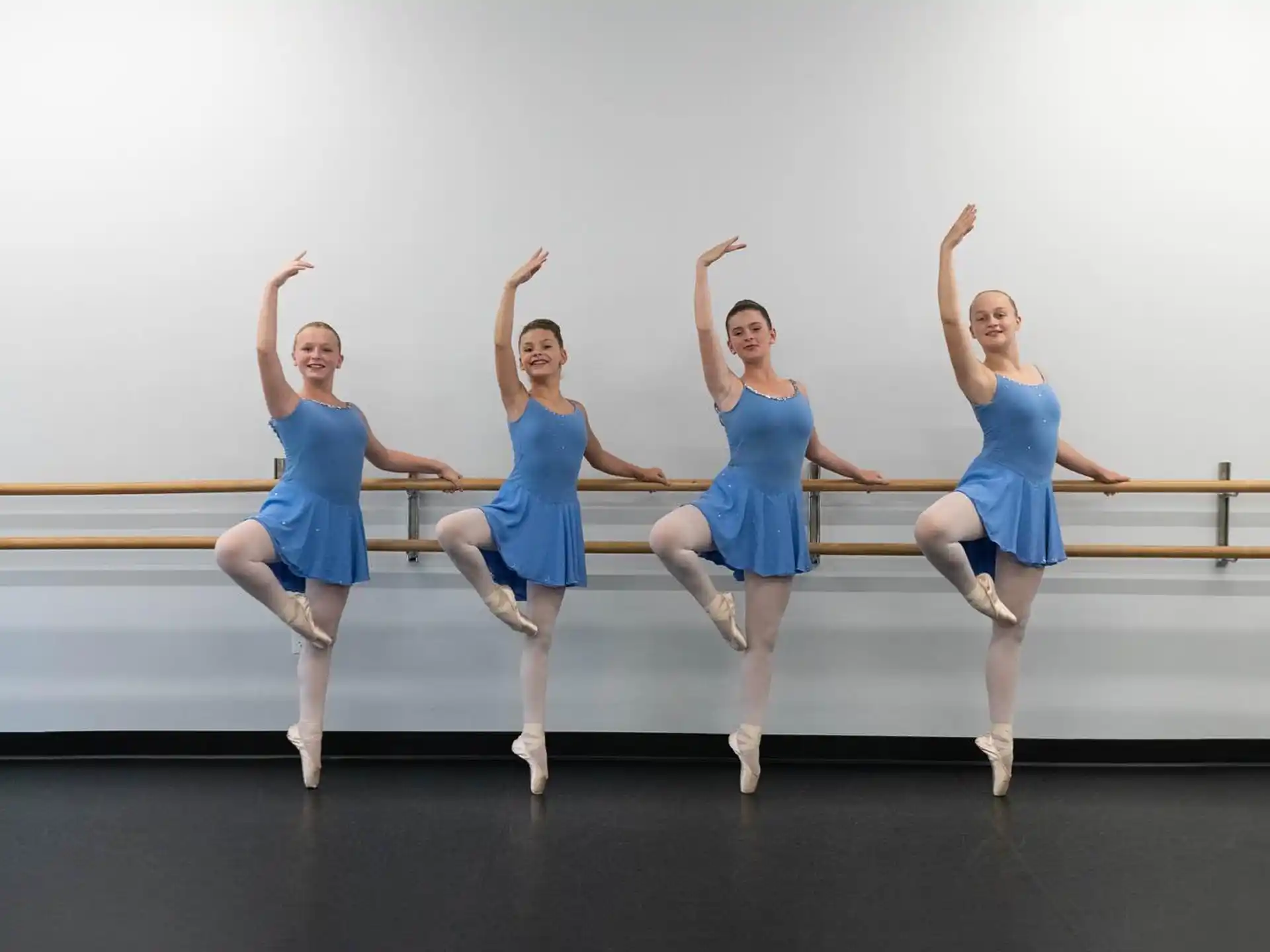 a group of women in blue dresses jumping in the air