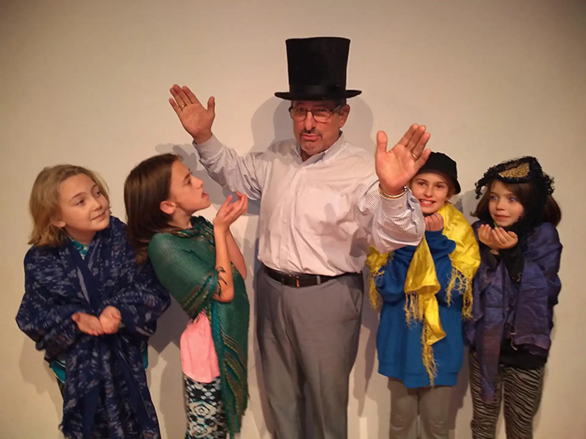 a man in a hat with his arms raised in front of a group of children
