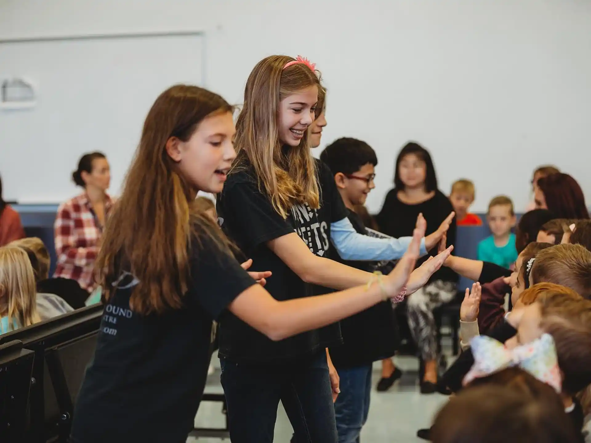 a couple of girls hugging in front of a group of people
