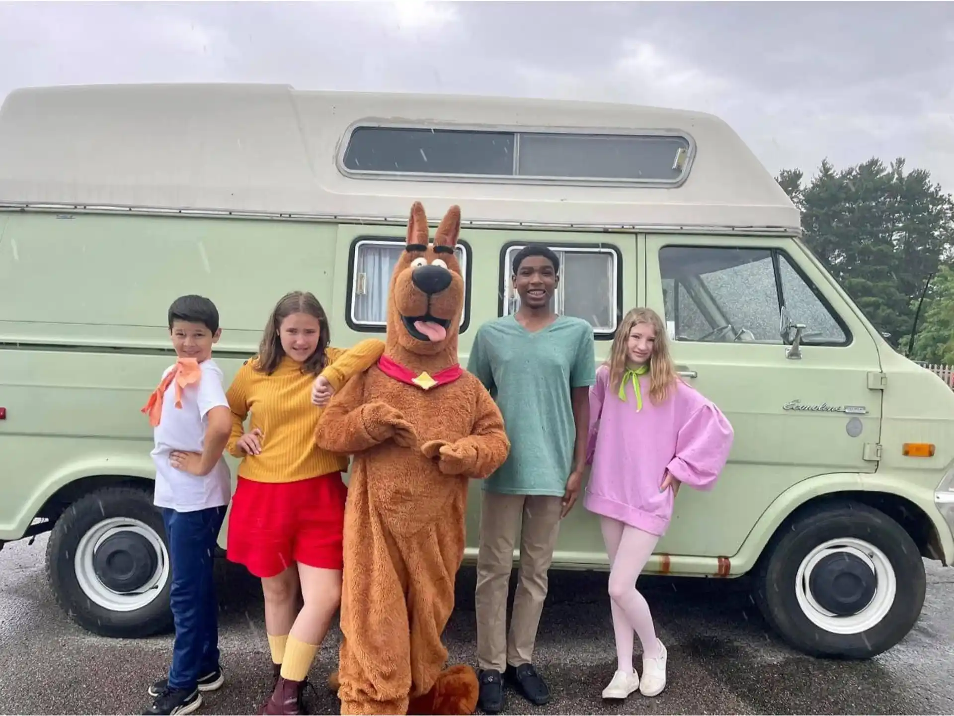a group of people posing with a person in a bear garment