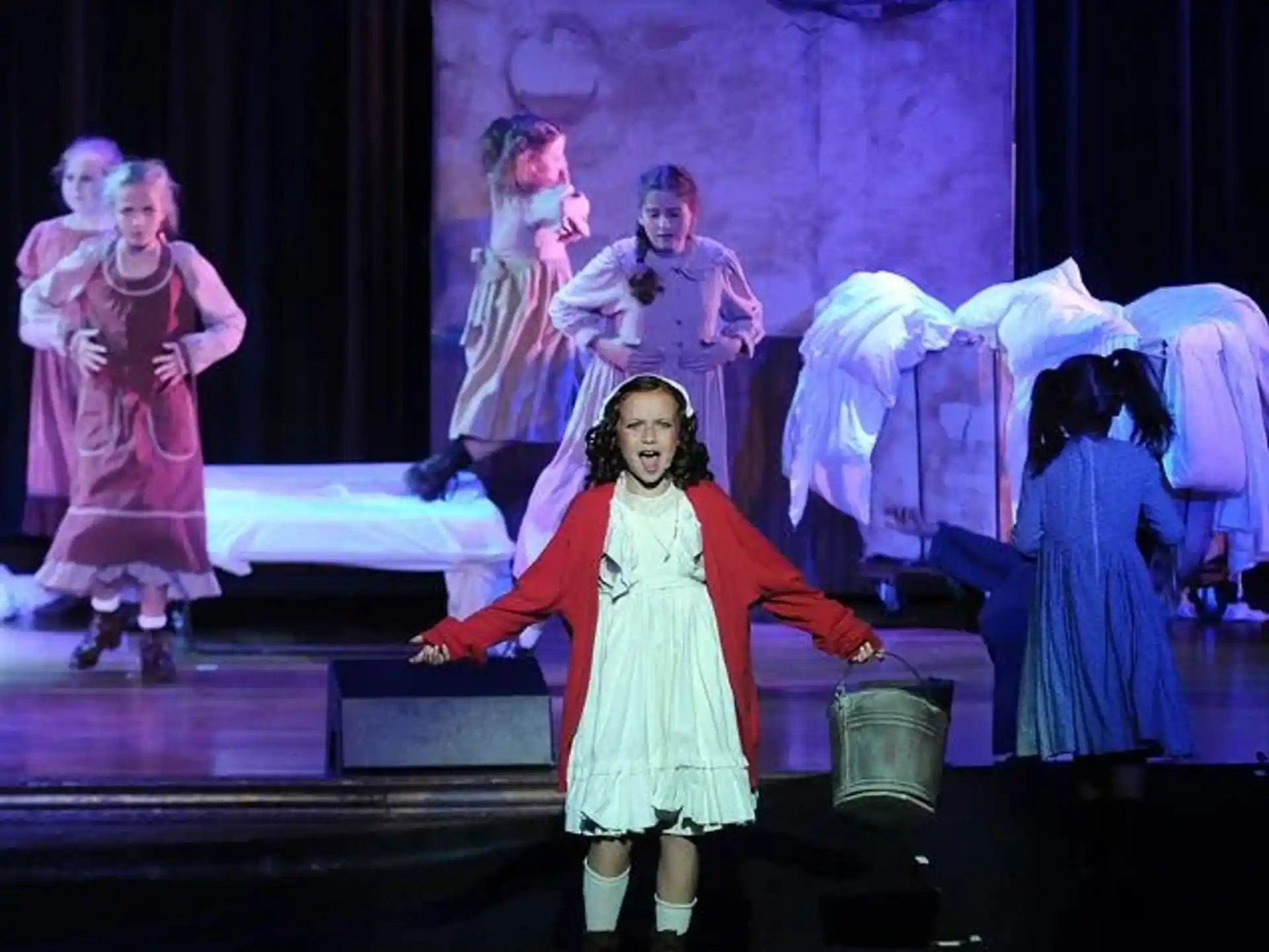 a girl in a dress dancing on a stage with other people