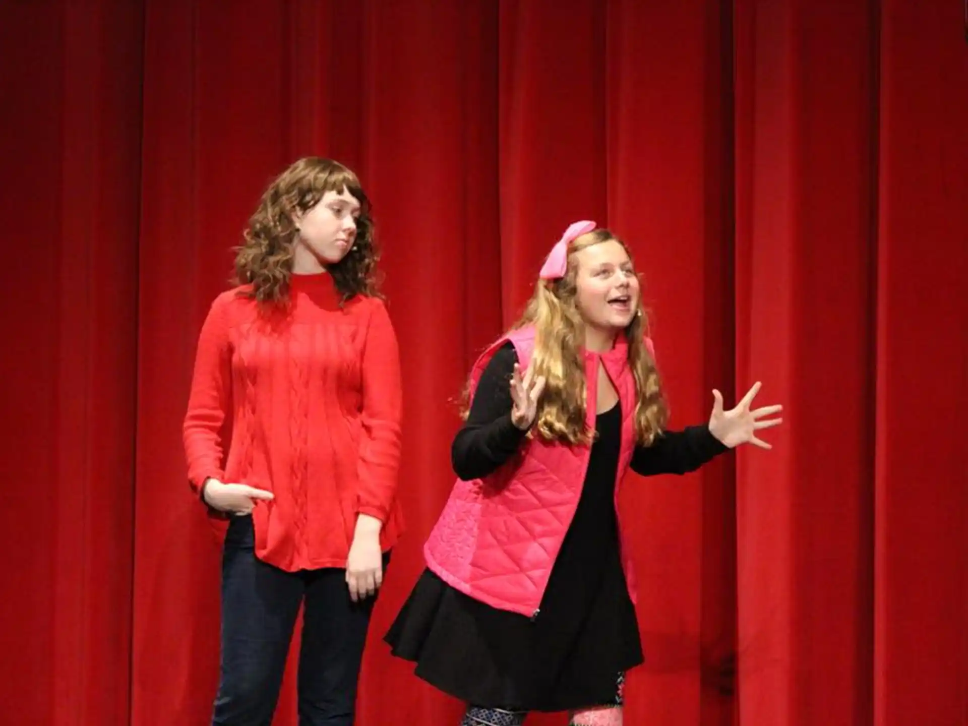 a couple of women standing in front of a red curtain