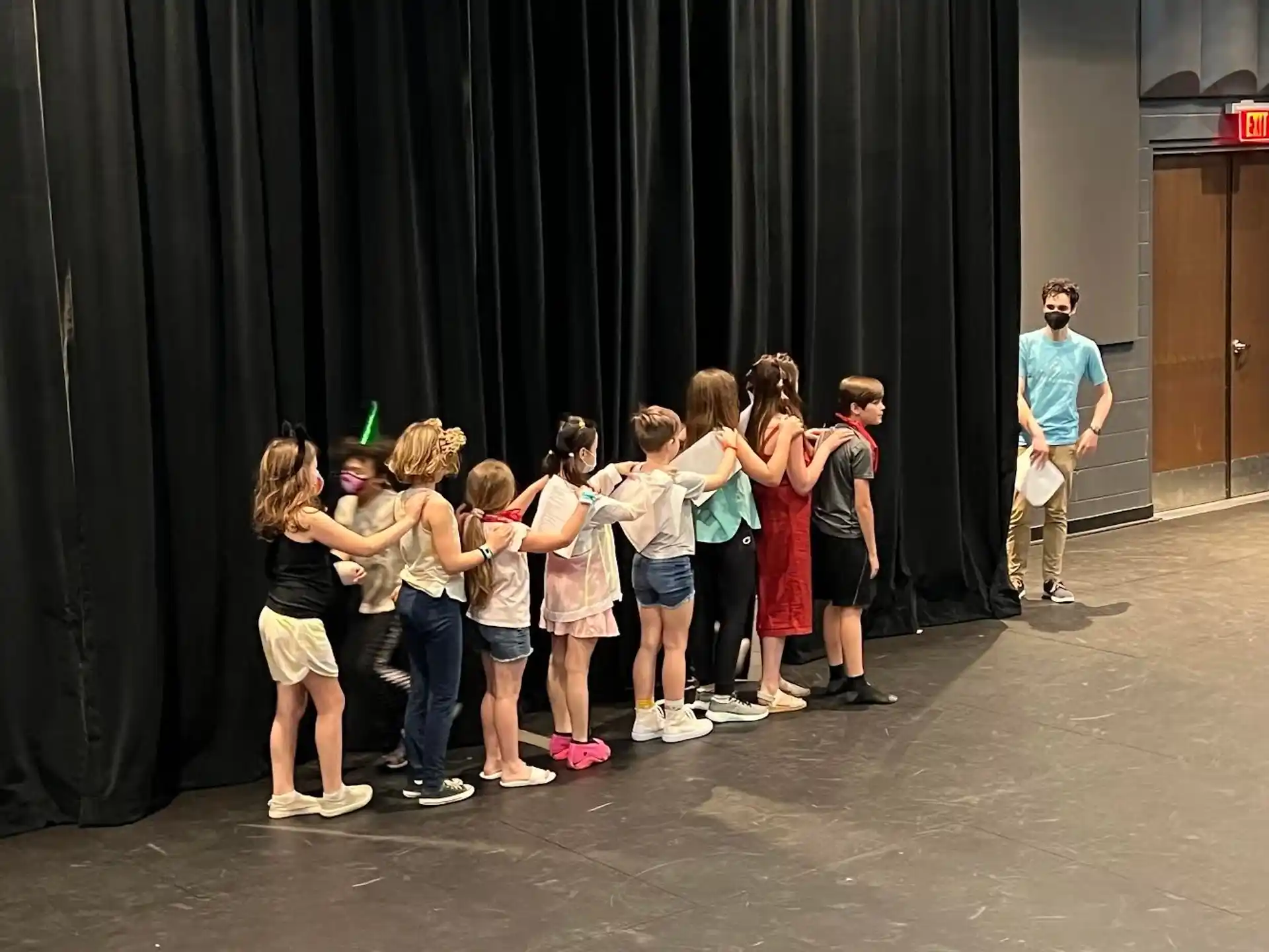 a group of children standing in front of a curtain