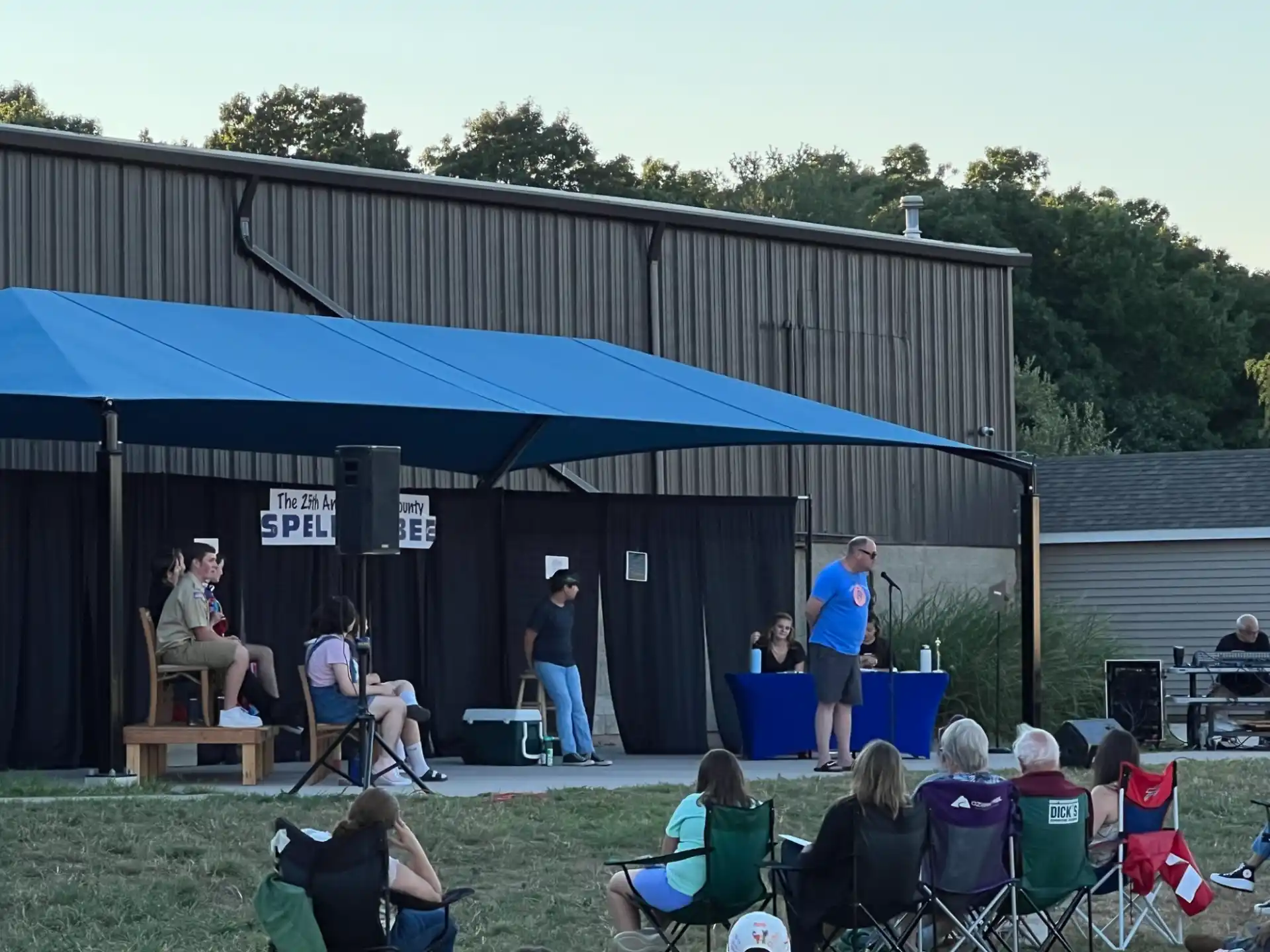 a group of people sitting under a blue tent