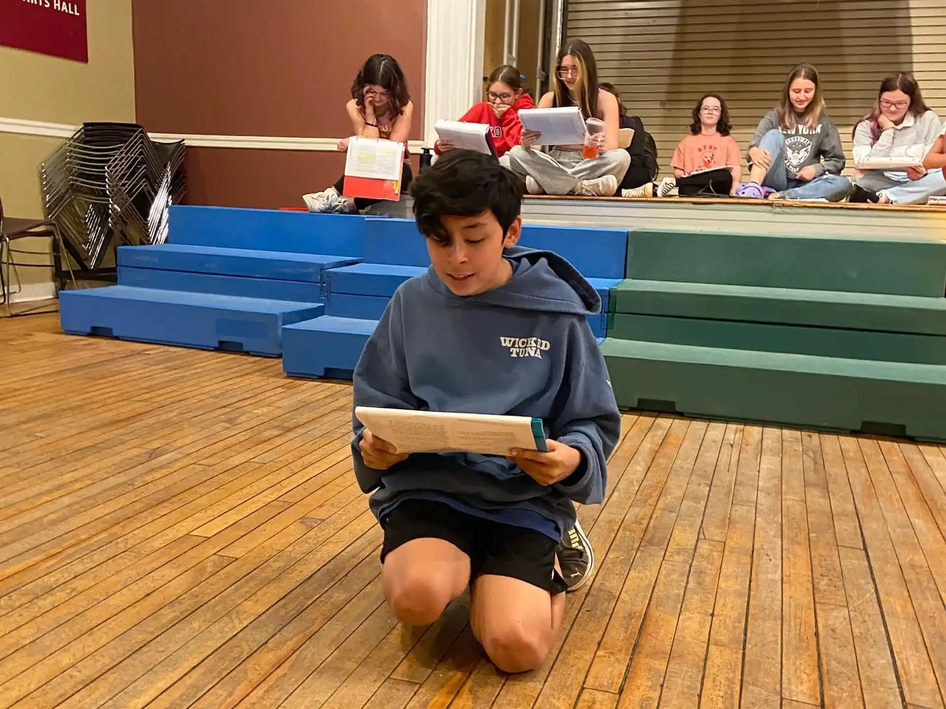 a boy sitting on the floor reading a book
