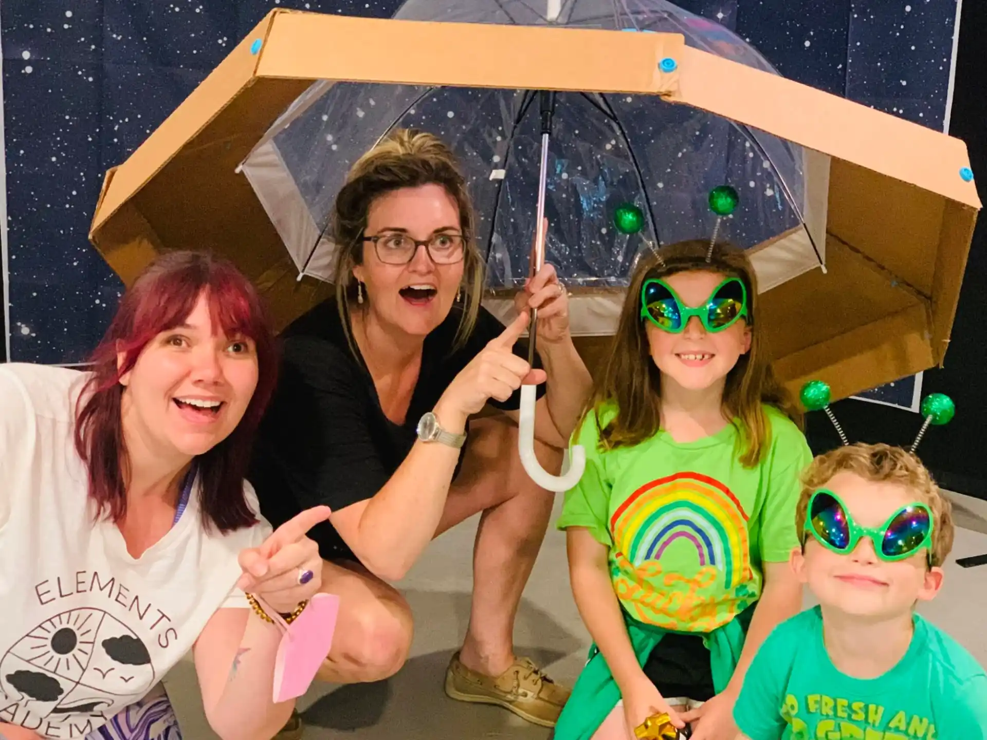 a group of people posing for a photo under an umbrella